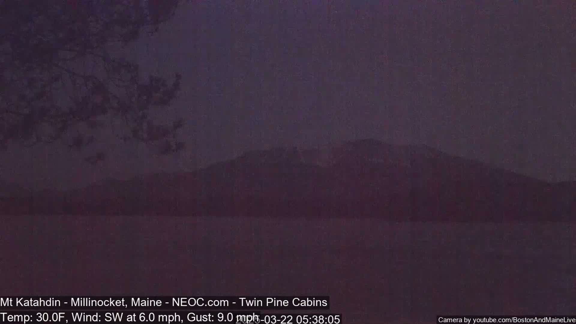 A dark, silhouetted mountain range is visible at dusk under a dim, dusky sky with a southwest wind.