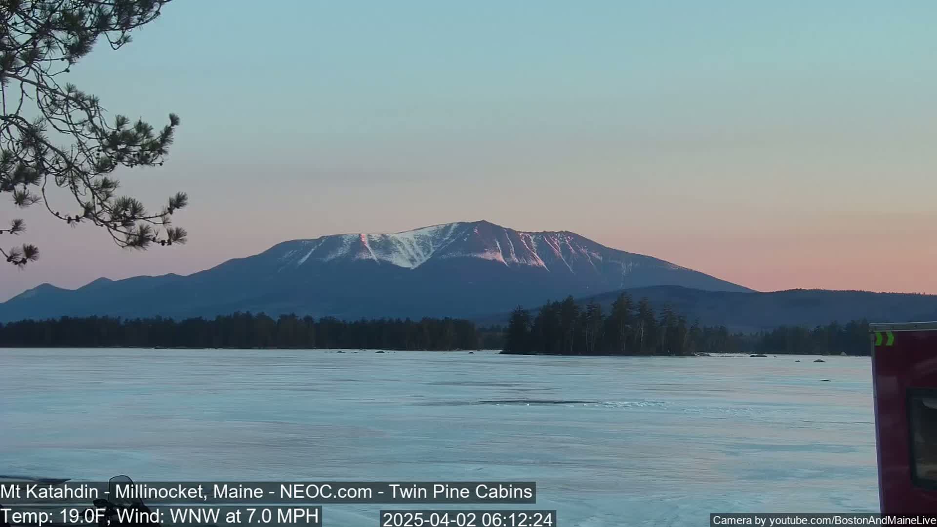 A snow-capped mountain is visible at dusk over a partially frozen lake, with a light wind blowing.
