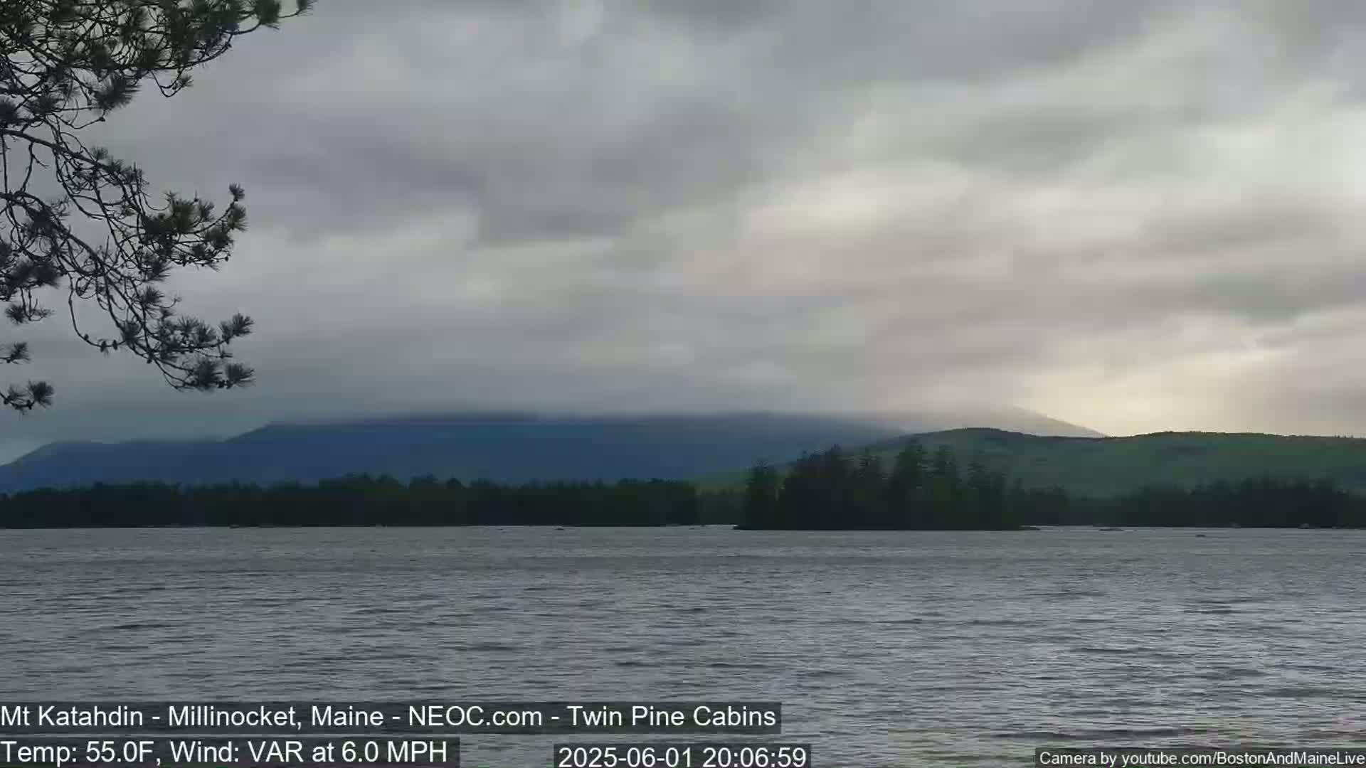 A calm lake with a distant mountain range under a cloudy sky.