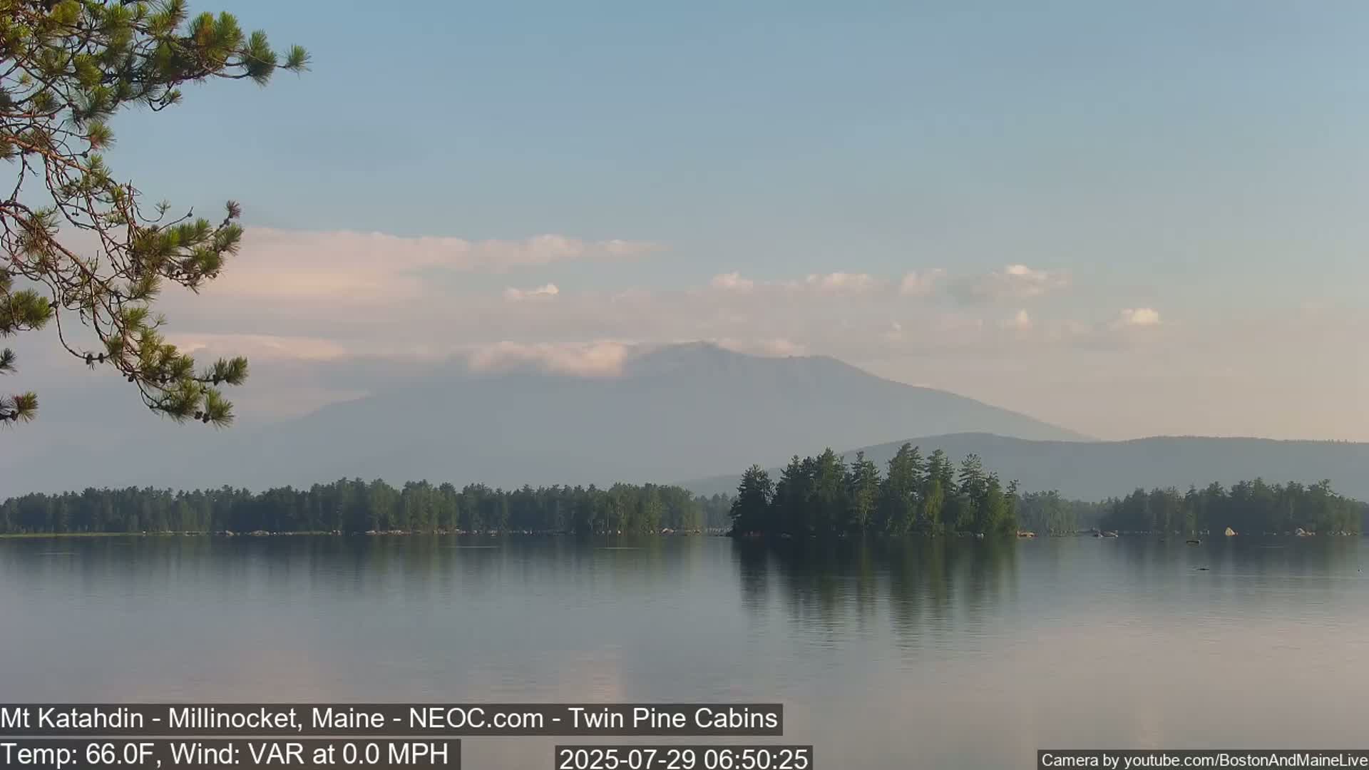 A calm lake with a distant mountain range under a hazy sky.