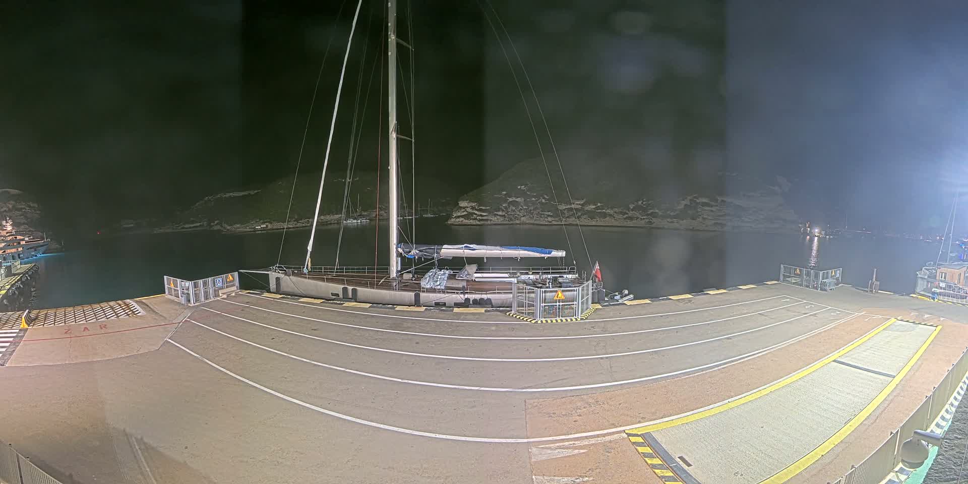 A large sailboat is docked at a harbor at night, under a dark sky.