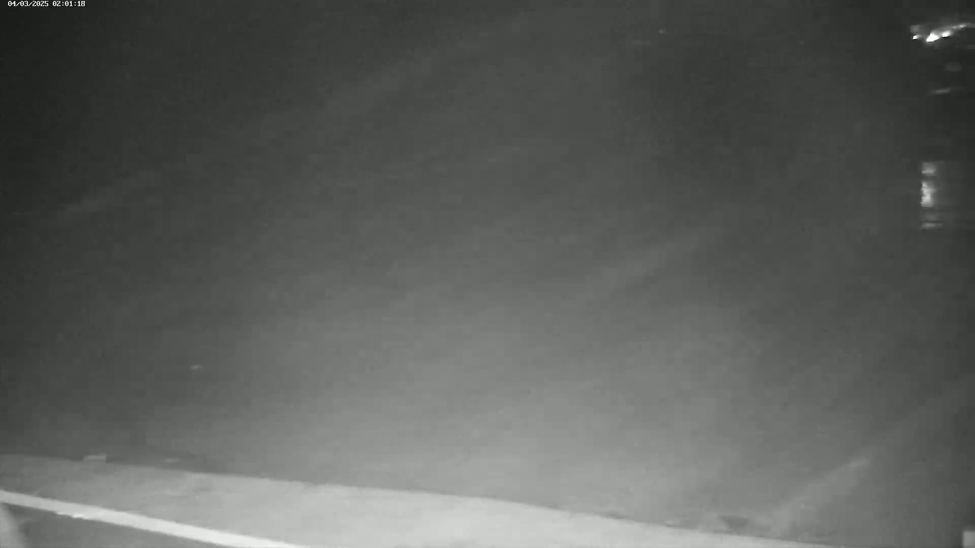 A low-light nighttime image shows a mostly obscured view of an outdoor area, possibly a yard or field.