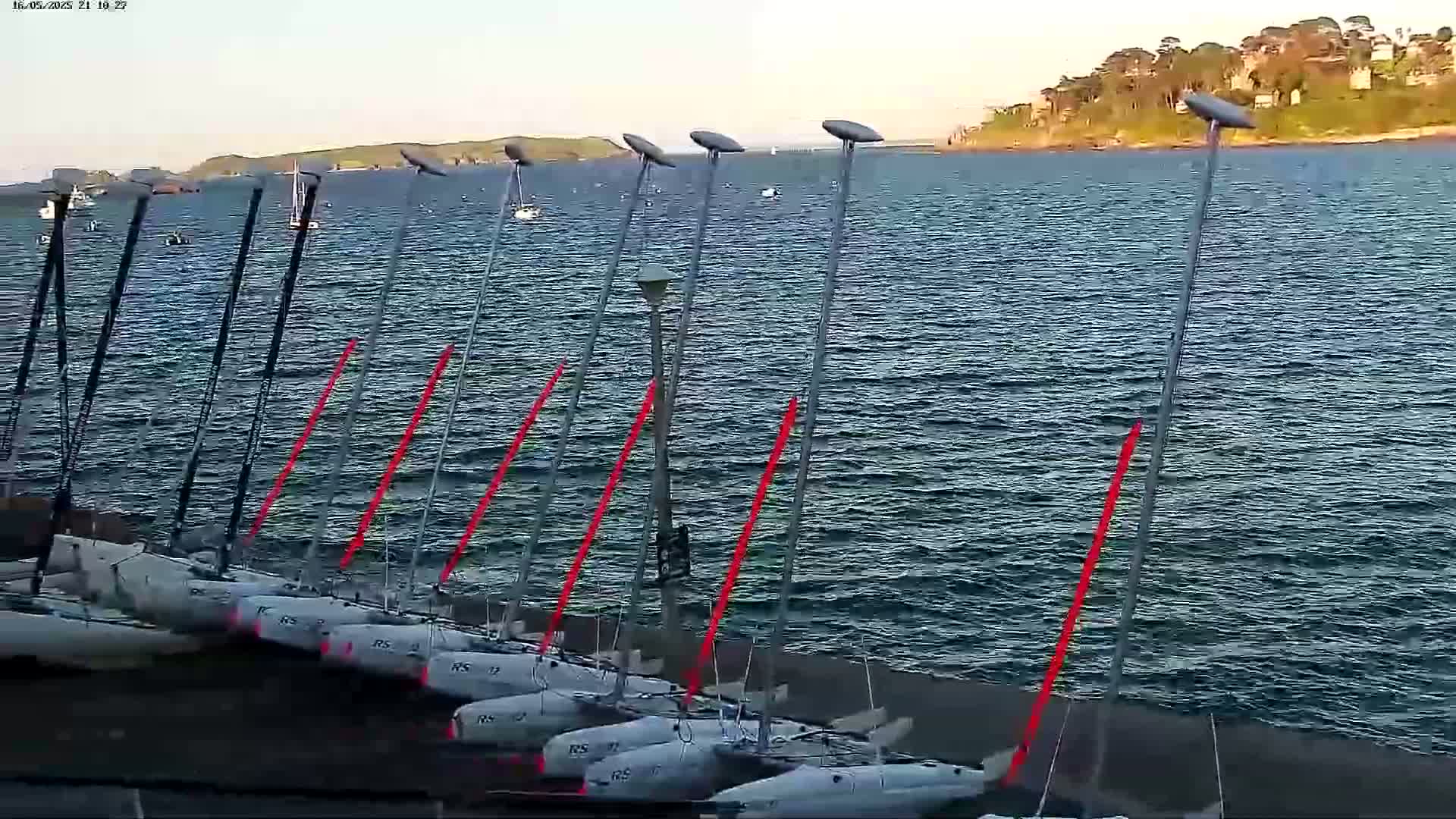 Several small sailboats are beached near a body of water under a mostly clear sky.