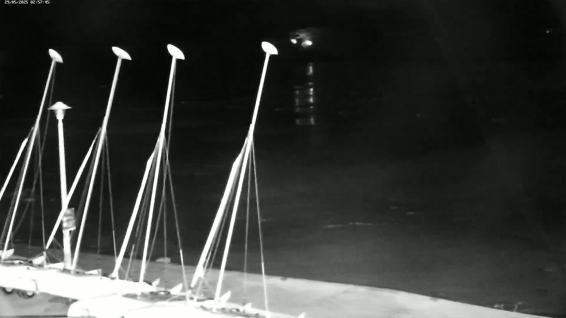Several sailboats are moored at a dock at night, under a dark sky.