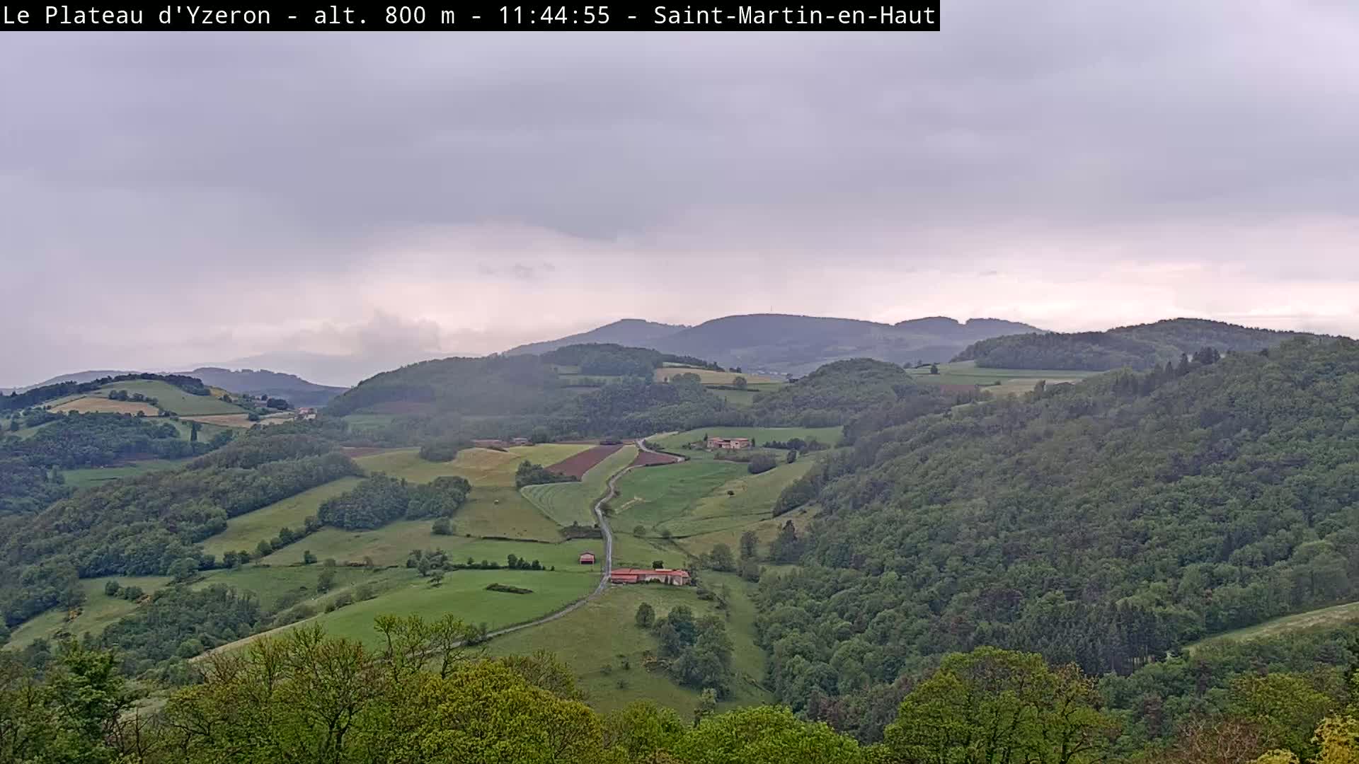 A rolling landscape of green hills and forests under an overcast sky.