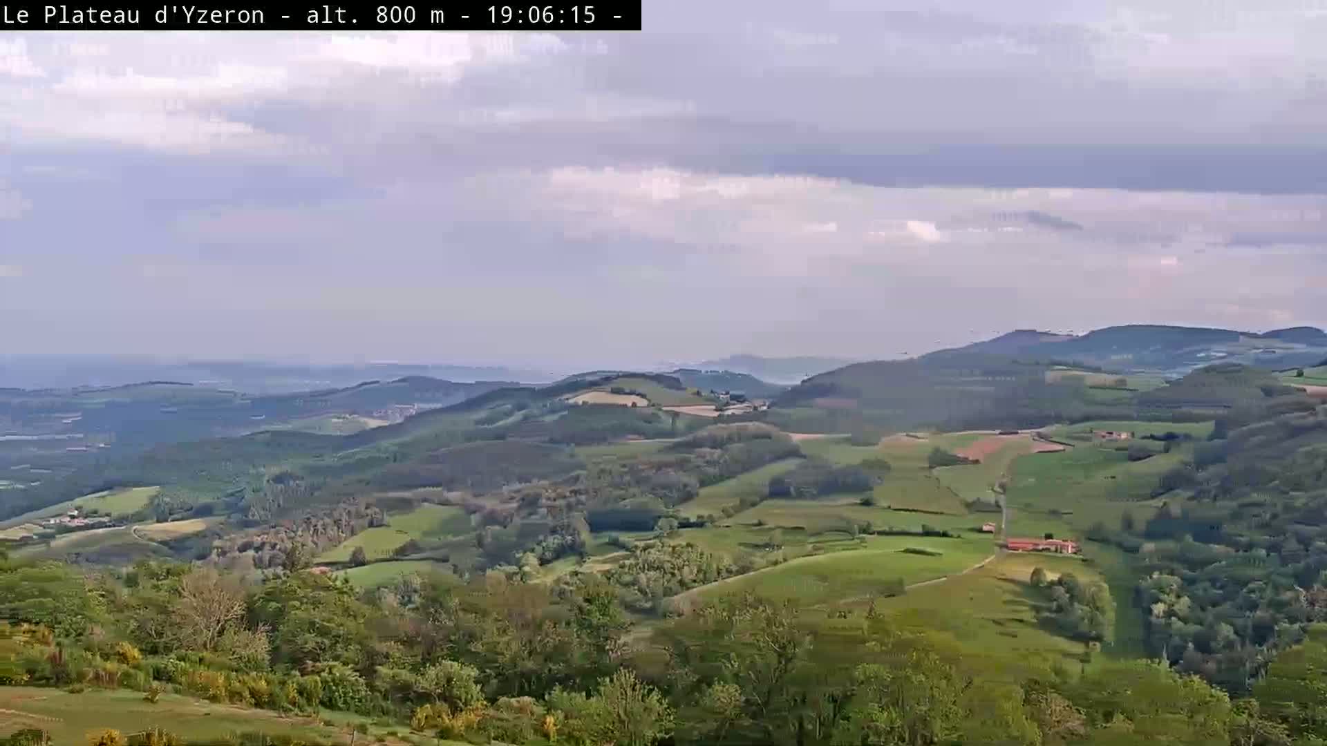 A sprawling landscape of rolling green hills and valleys under a mostly cloudy sky.
