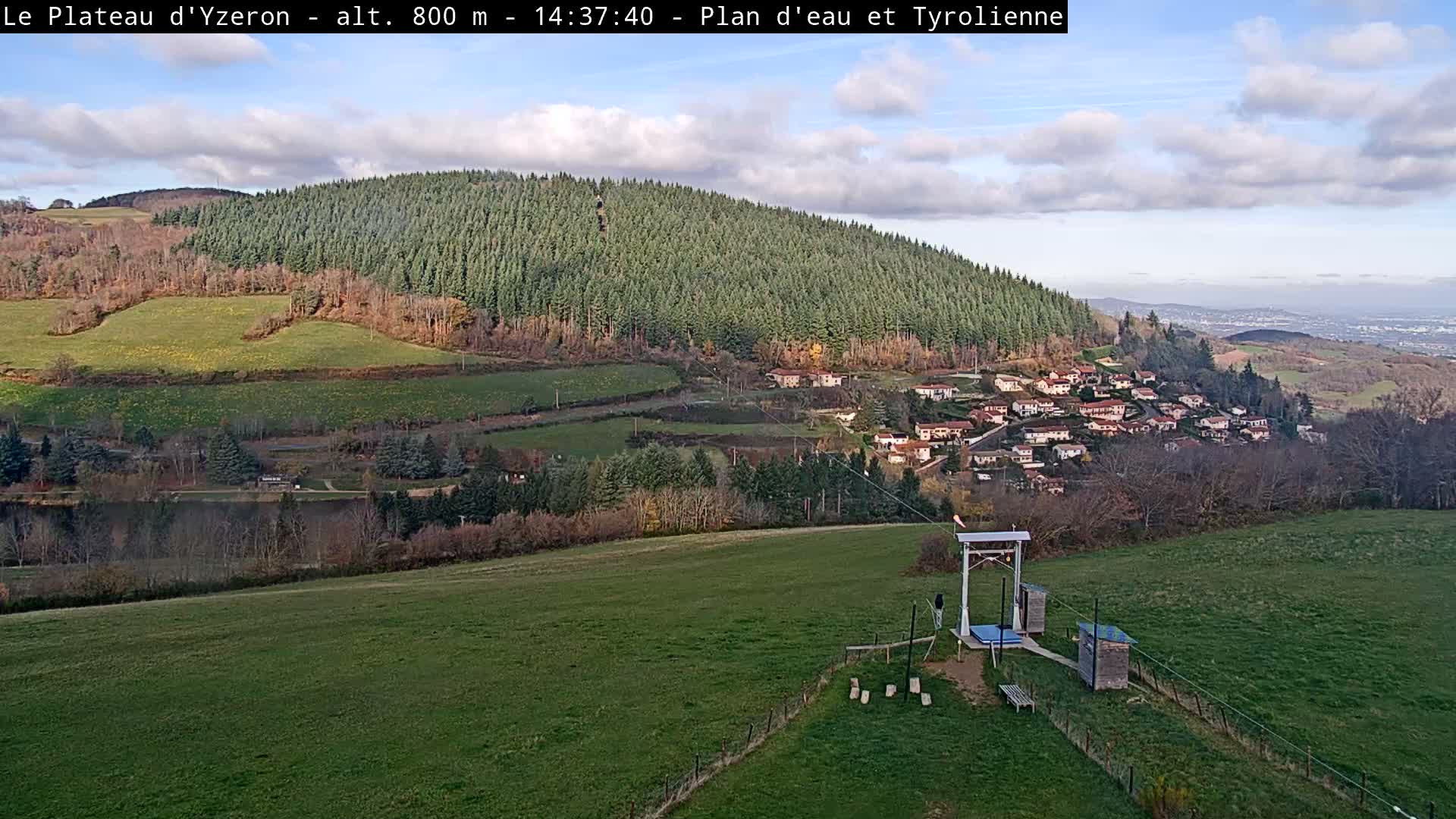A cloudy day reveals a panoramic vista of rolling hills dotted with scattered villages and patches of green fields, all under a grey, overcast sky.