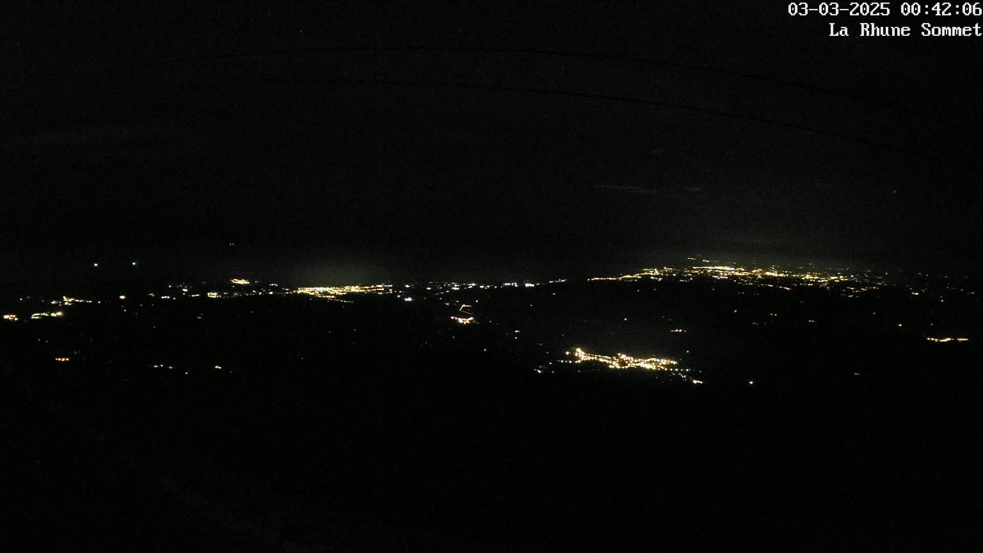 A nighttime view of a sprawling city's lights spread across a dark landscape.