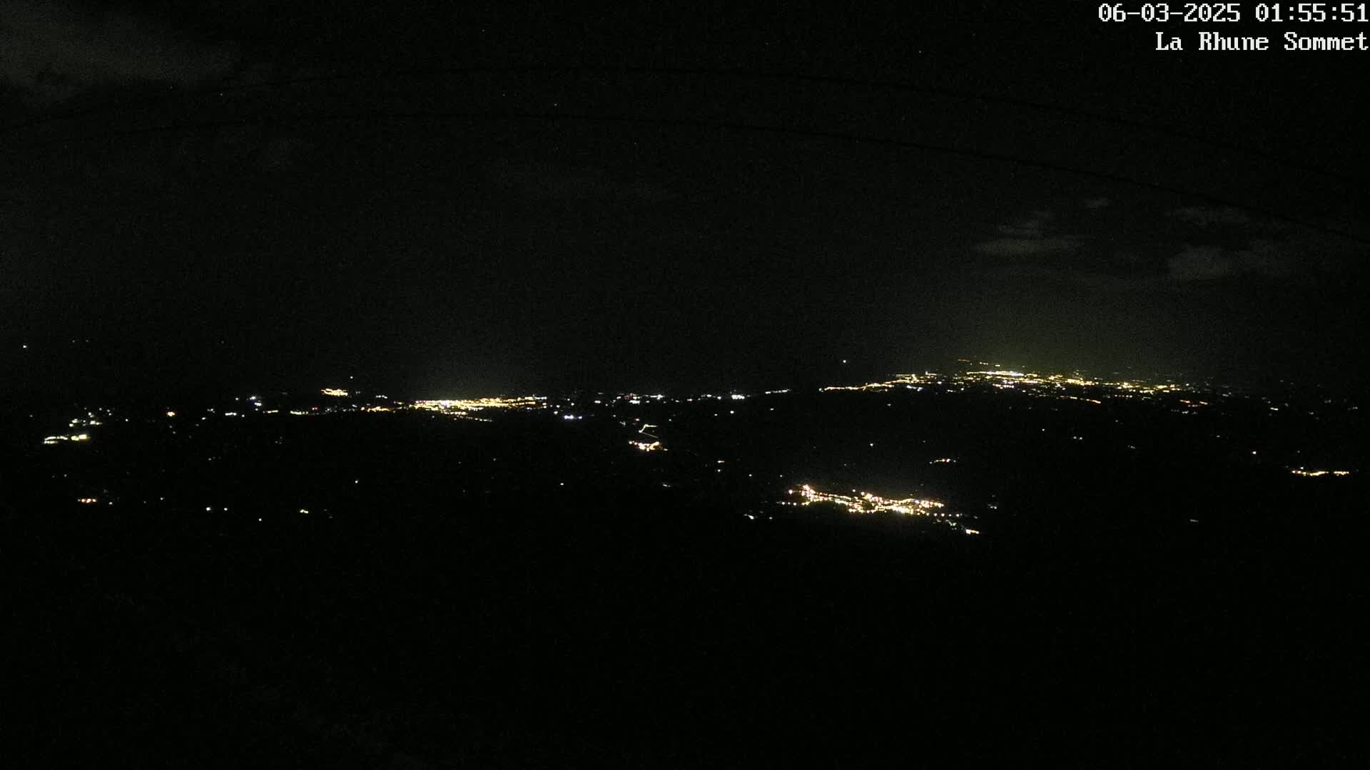 A distant cityscape glows with scattered lights under a dark, clear night sky.