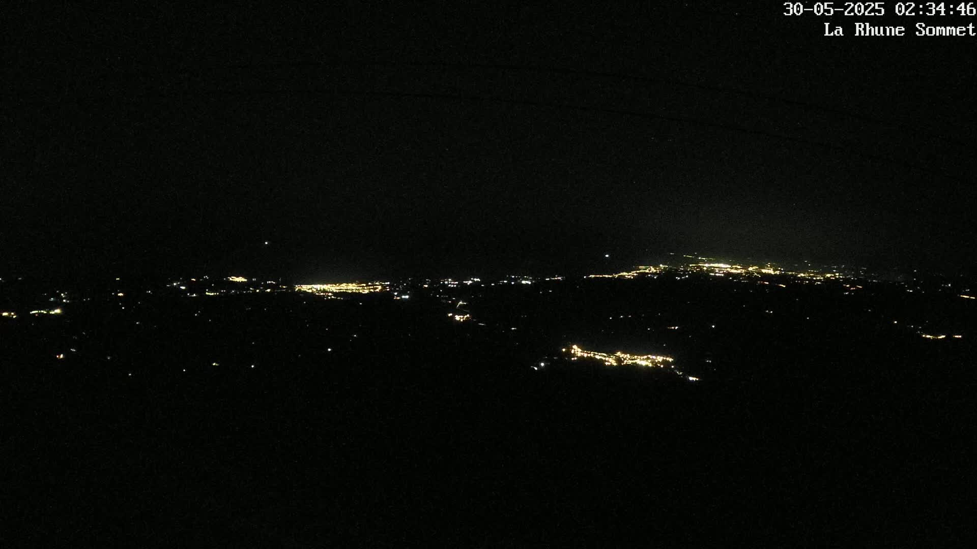A nighttime, long-range view of a distant city's lights spread across a dark landscape.