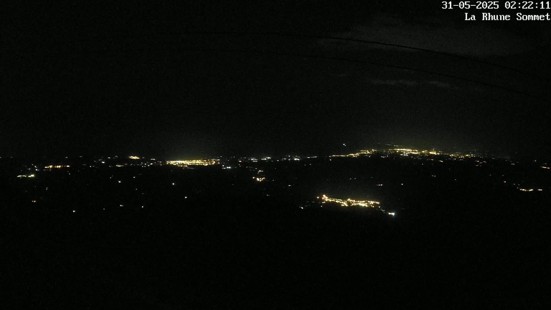 A nighttime view shows a distant city's lights scattered across a dark landscape.