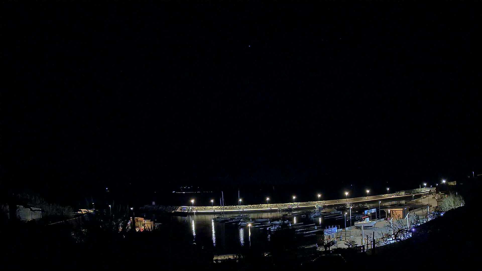 A nighttime view of a marina with numerous boats docked under a clear, dark sky.