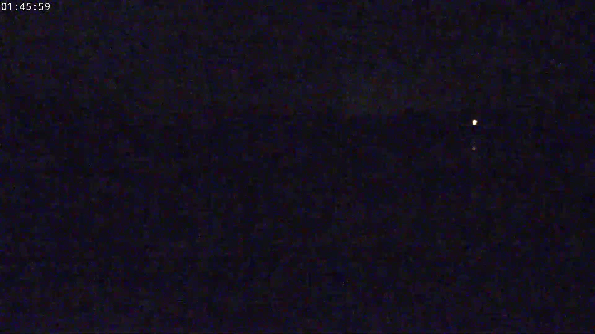 A dark, nighttime scene shows two faint lights in the distance.