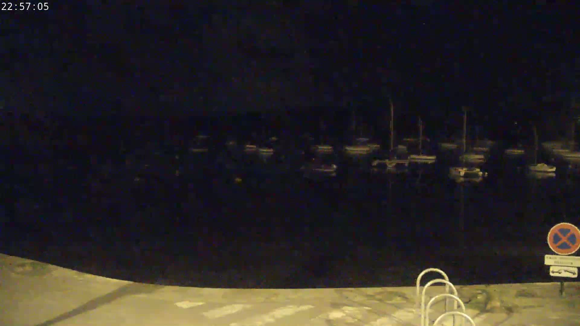 A nighttime view of a marina with numerous boats docked, under a dark sky.