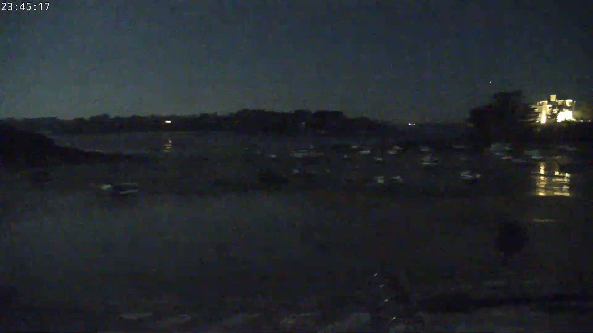 Numerous boats are moored in dark water under a night sky.