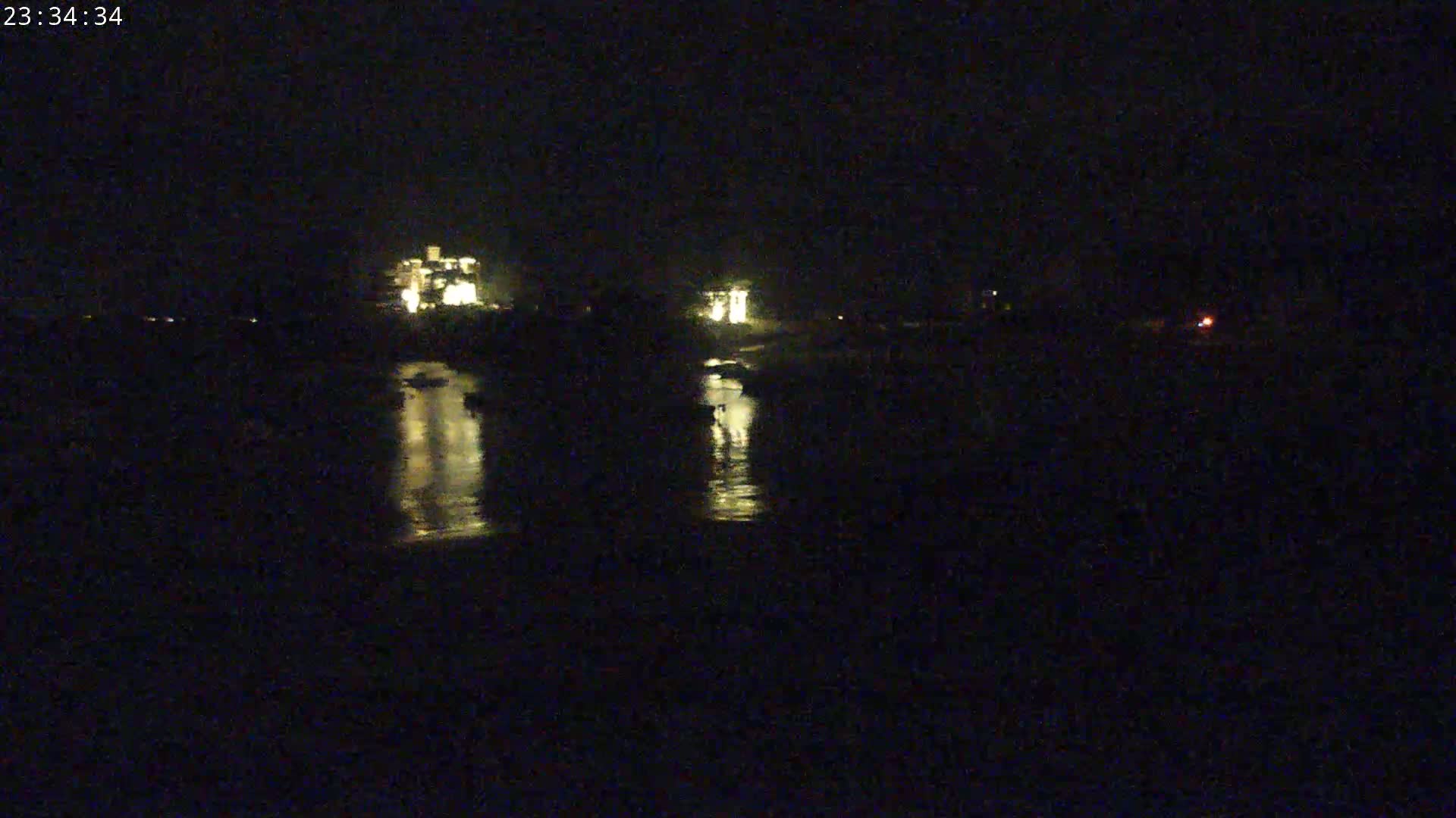 Lit buildings are reflected in dark water at night.