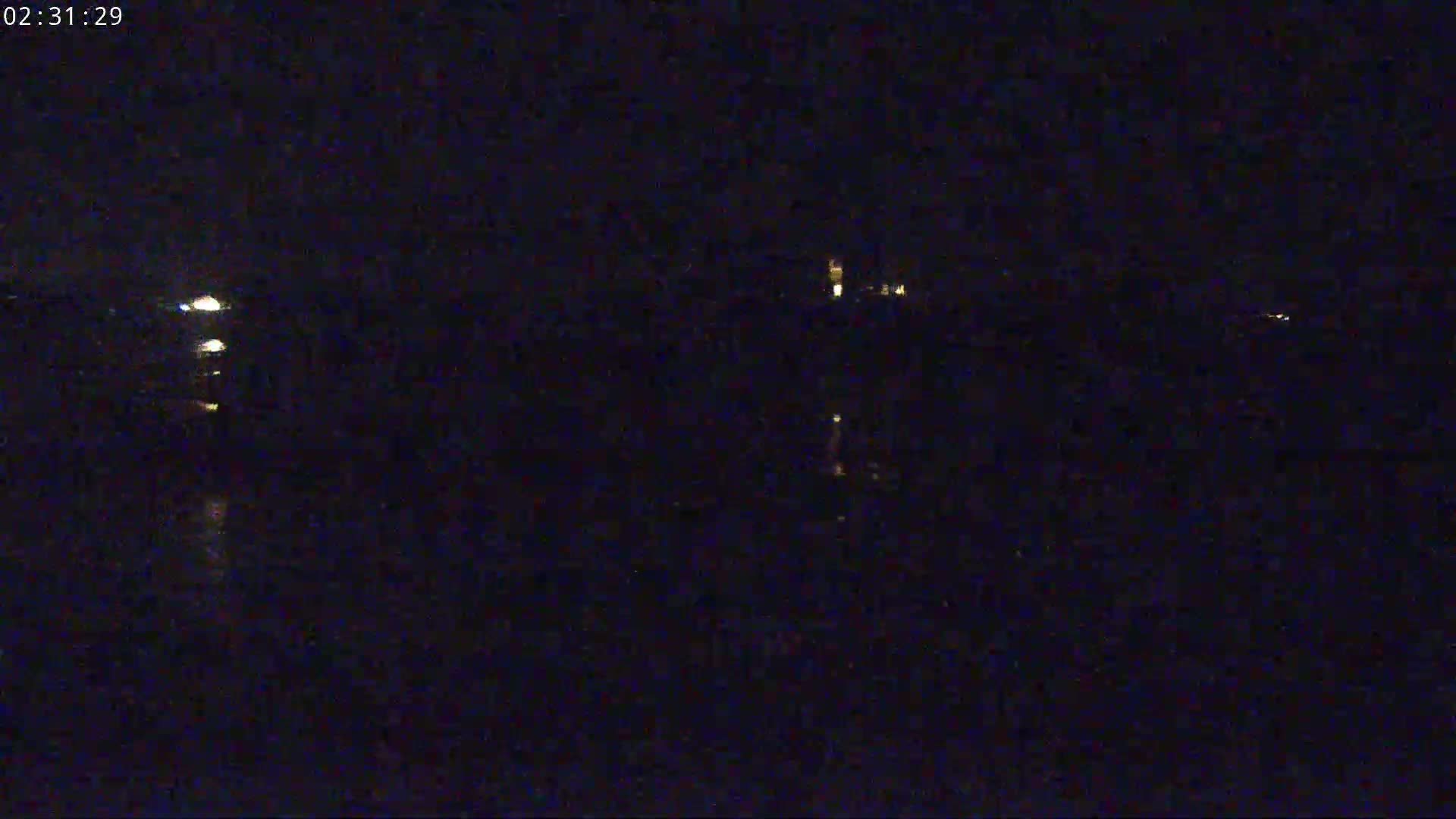 A nighttime, dark view of a body of water with faint lights visible in the distance.