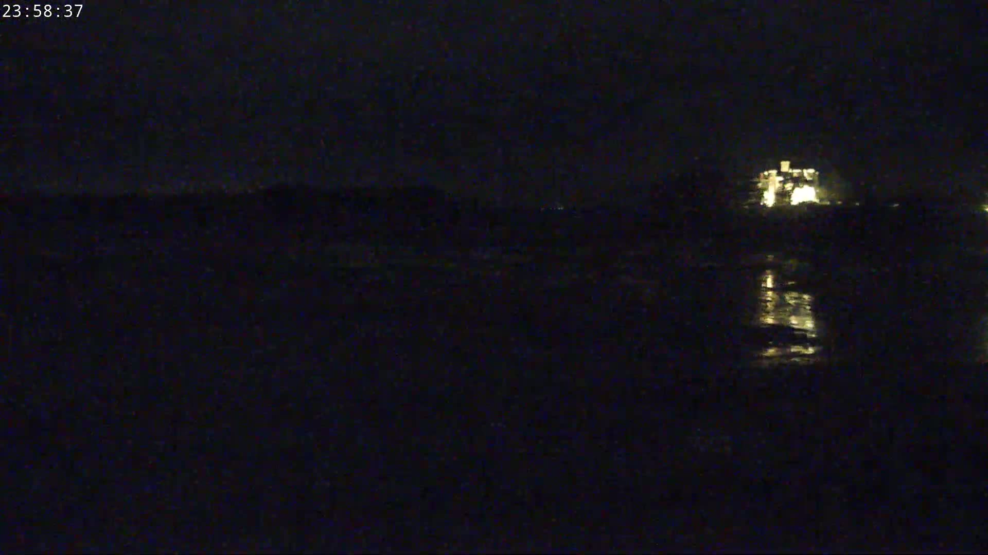 A dimly lit building is visible across a dark body of water at night.