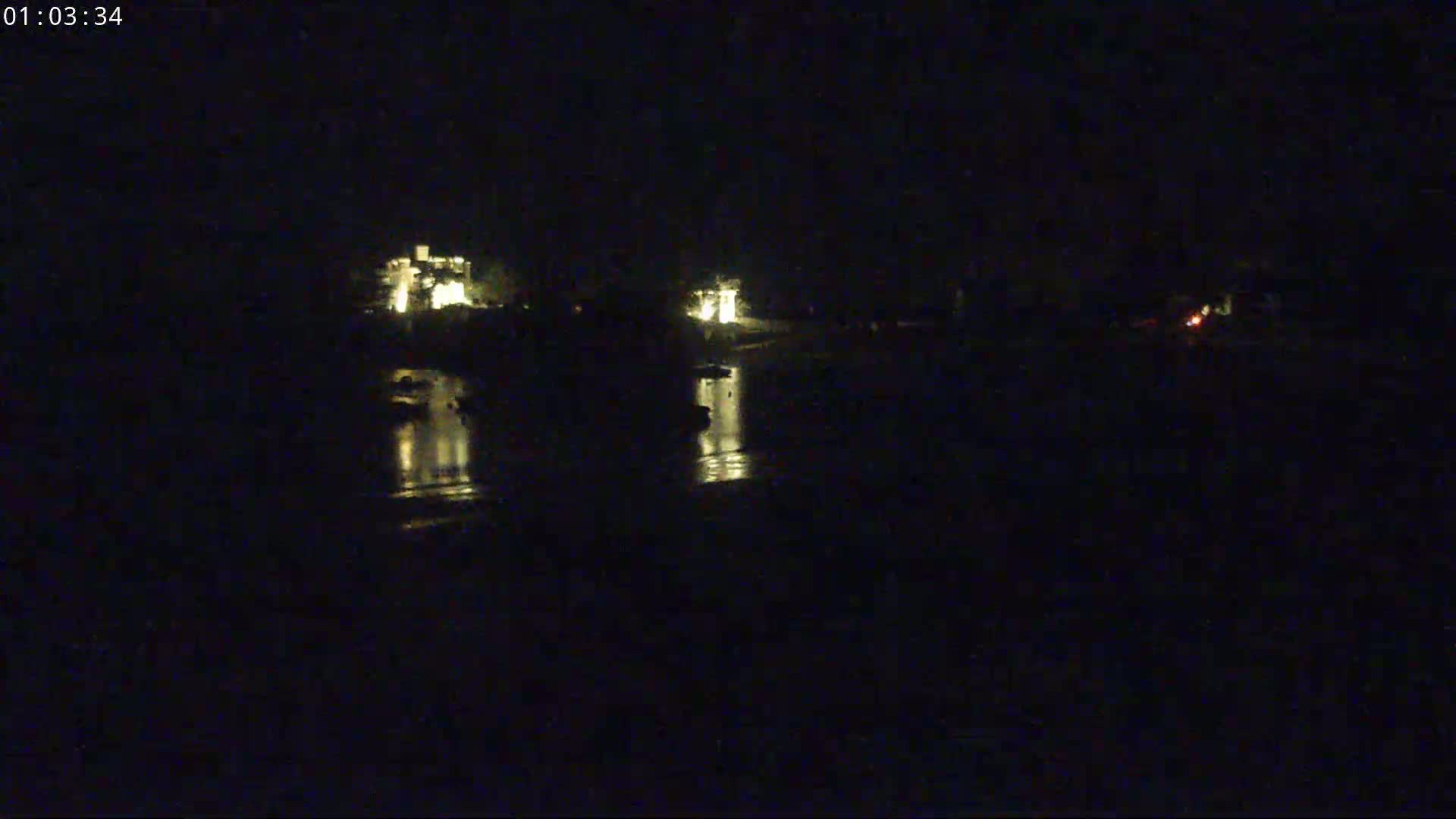 A nighttime view of dimly lit structures across a dark body of water.