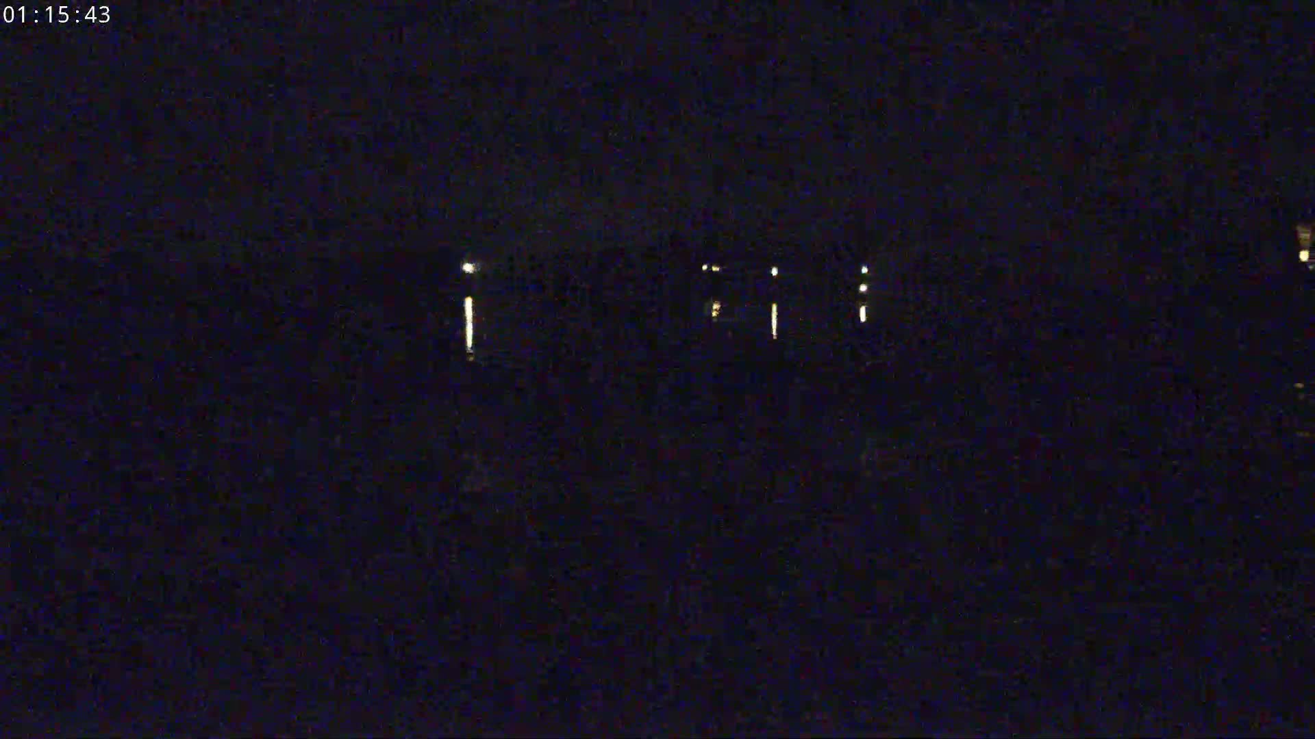 A dark, nighttime scene shows several distant lights illuminating a mostly obscured landscape.