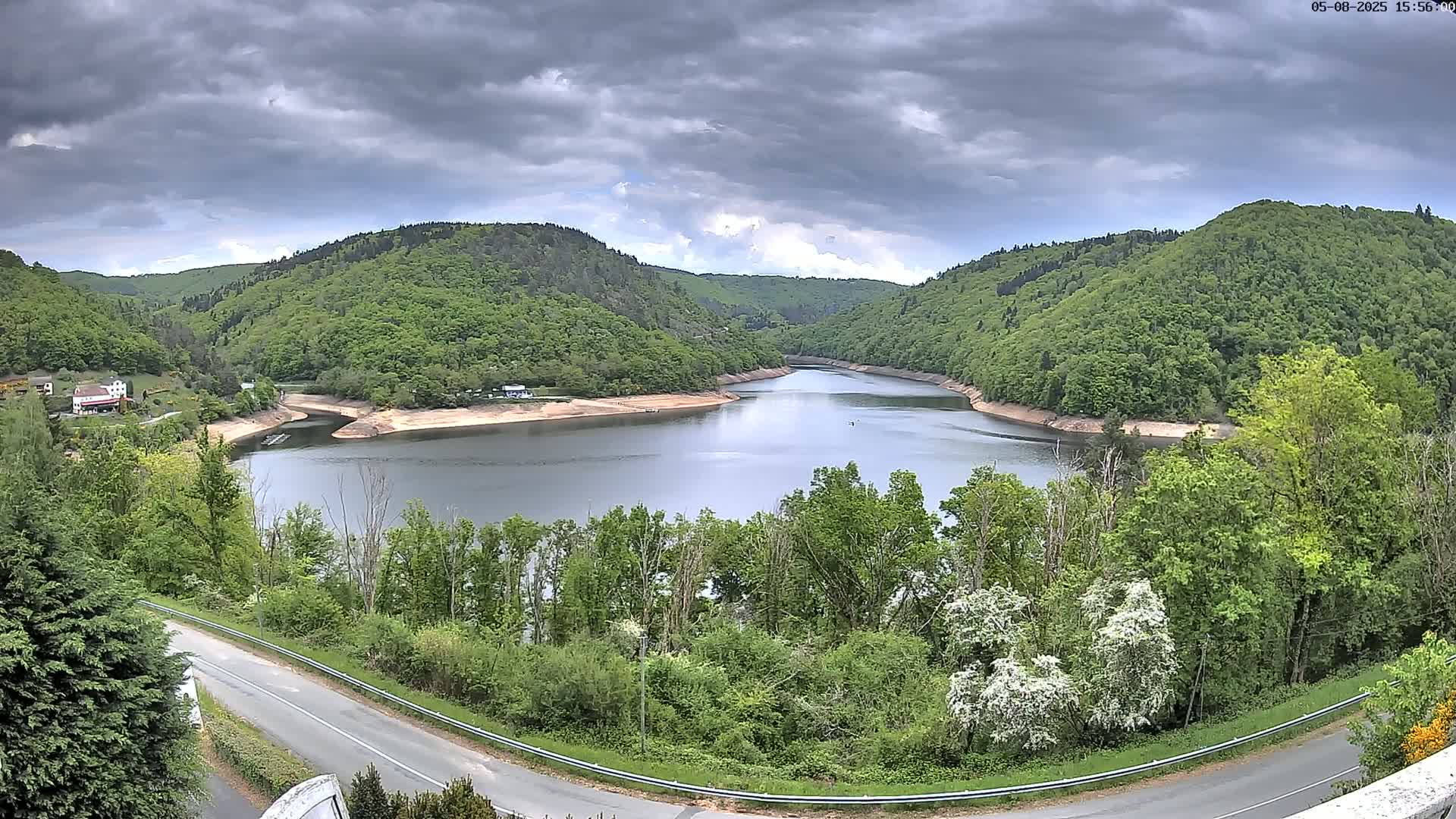 A winding river nestled in a valley of lush green hills under a cloudy sky.