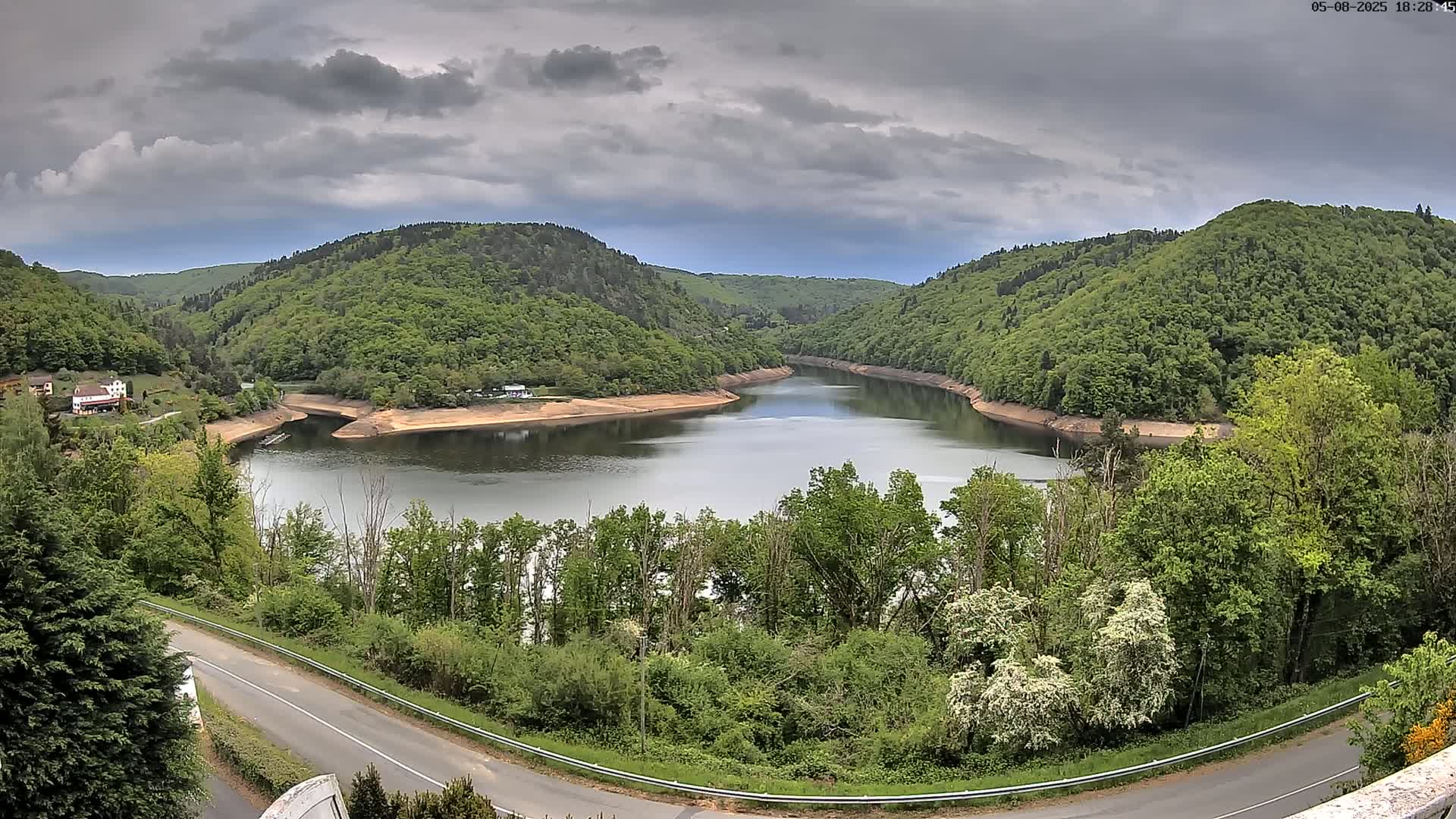 A winding river nestled in a valley of lush green hills under a cloudy sky.
