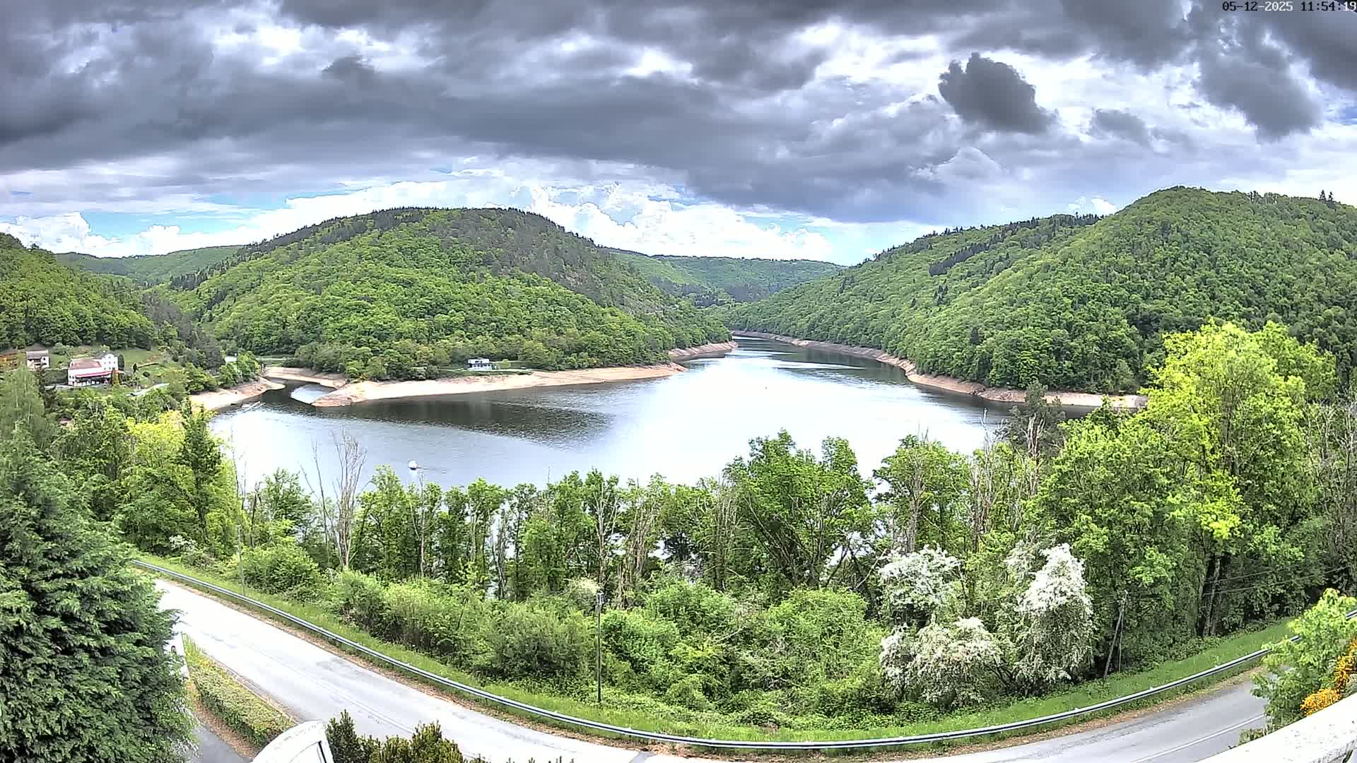 A winding river flows through a lush green valley under a cloudy sky.