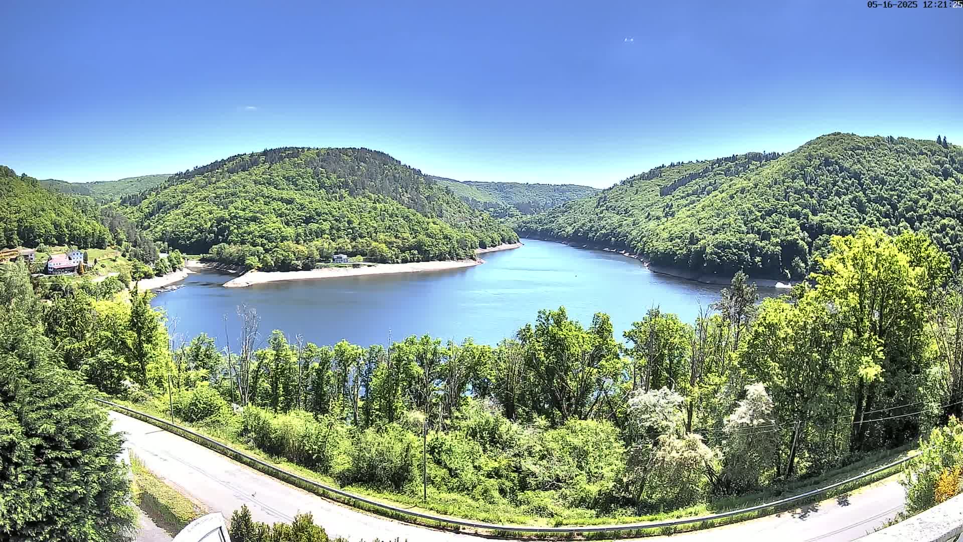 A winding river nestled within lush green hills under a clear blue sky.