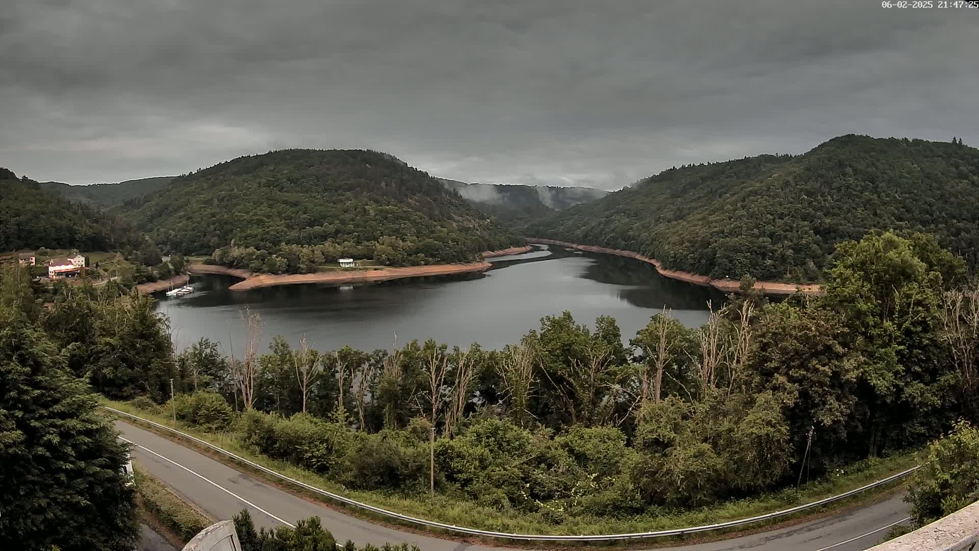 A winding river nestled in a valley of lush green hills under a cloudy sky.