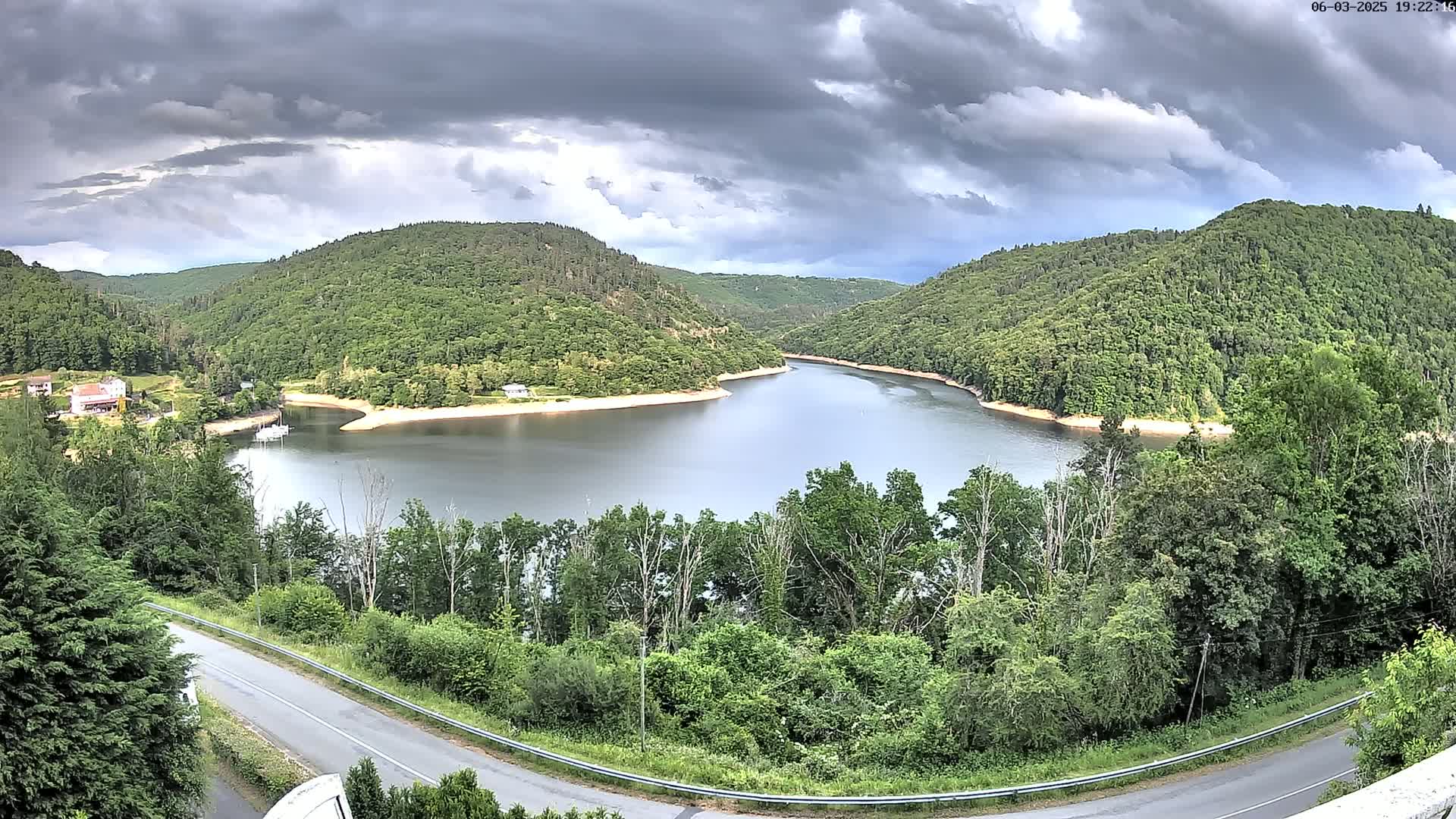 A winding river flows through a lush green valley under a cloudy sky.