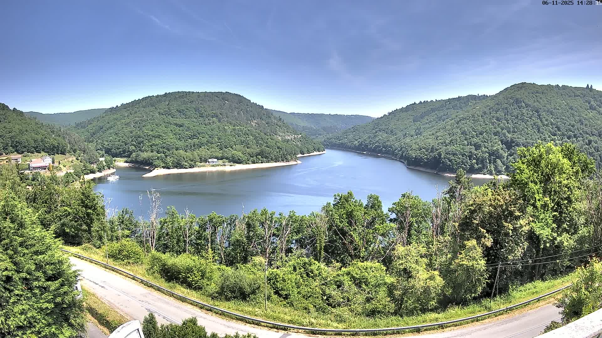 A winding river surrounded by lush green hills under a clear blue sky.