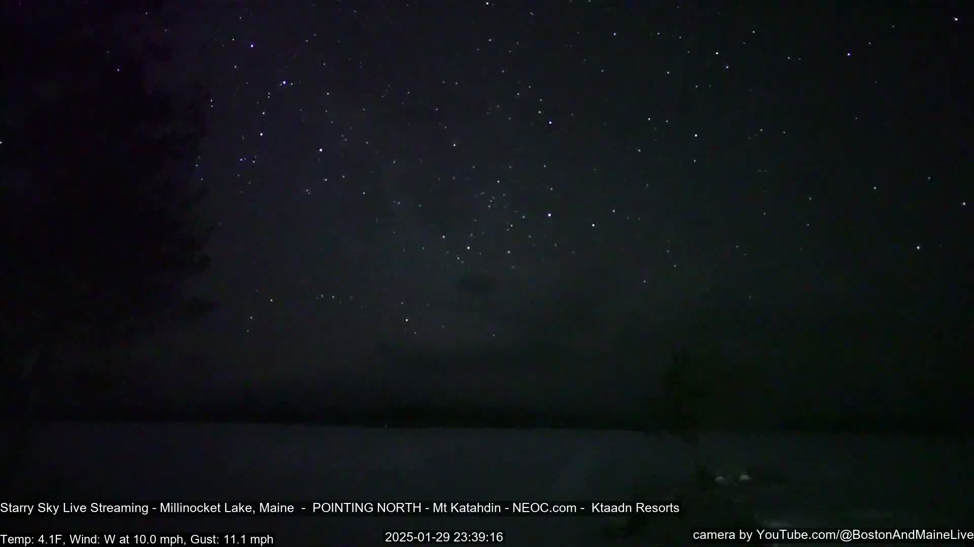 A nighttime view of a starry sky over a dark lake, with a 10 mph wind and gusts up to 11.1 mph at 4.1°F.