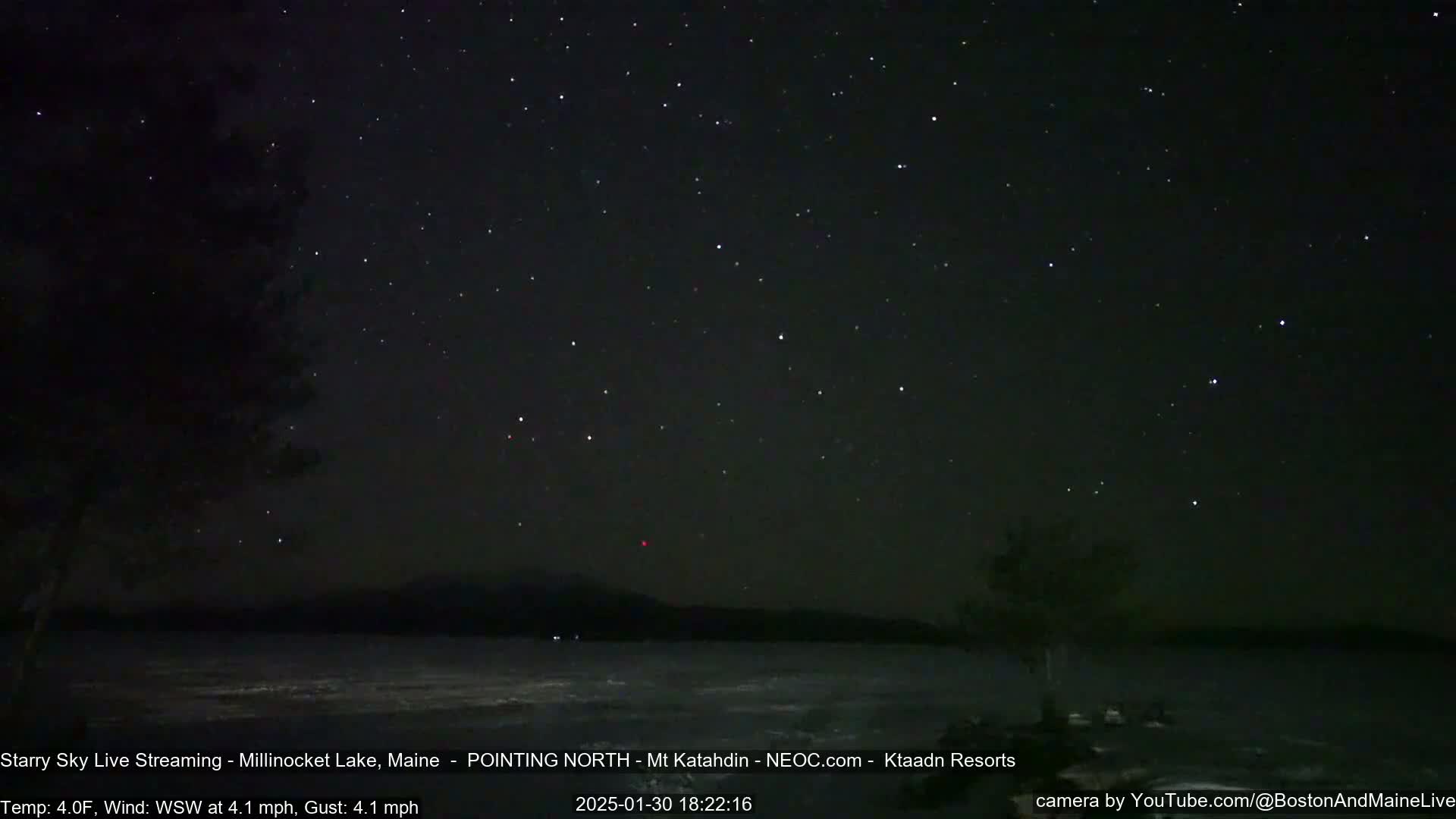 A nighttime view of a lake under a clear, starry sky with a calm wind.
