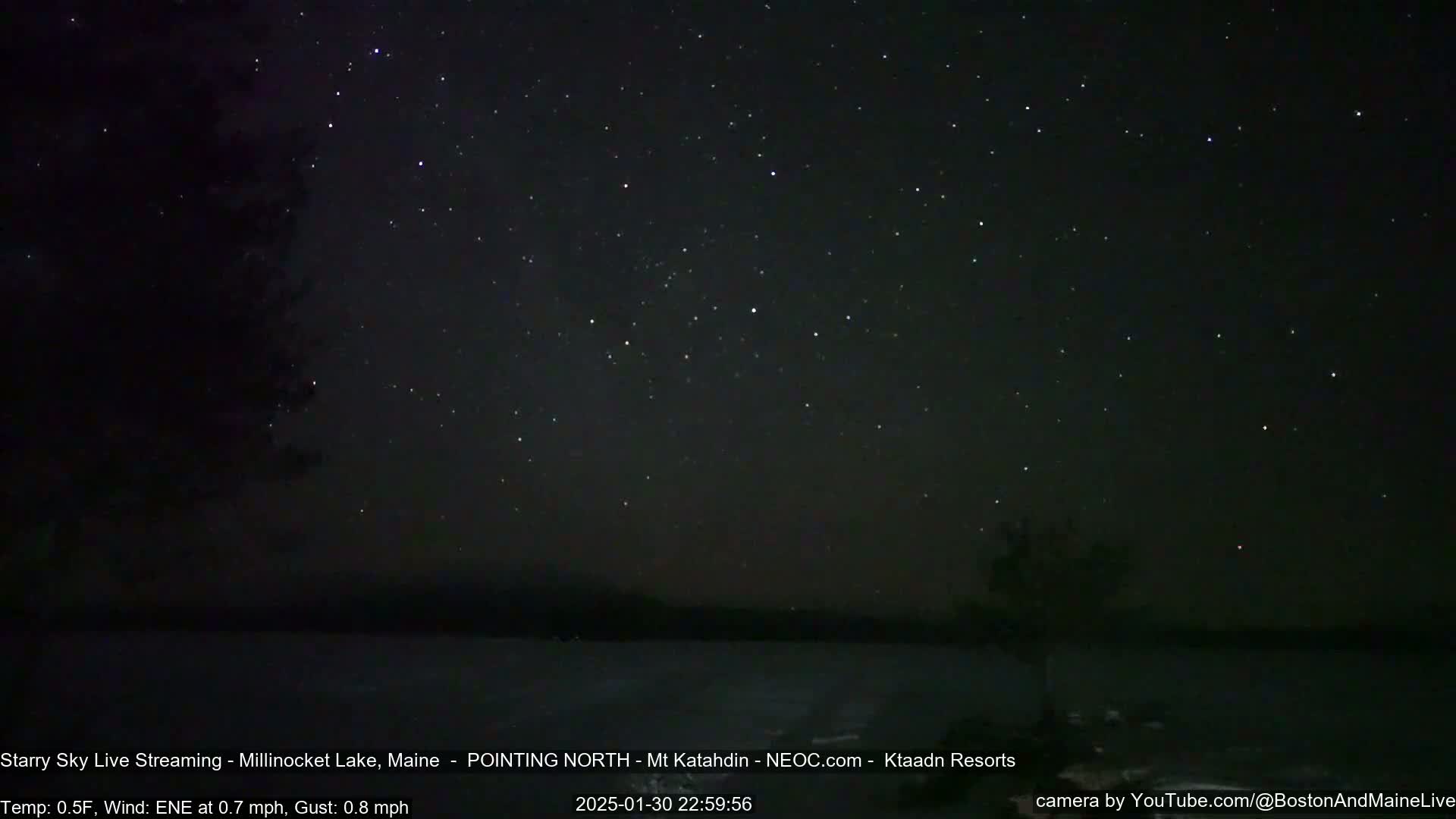 A dark, clear night sky filled with stars over a calm body of water.