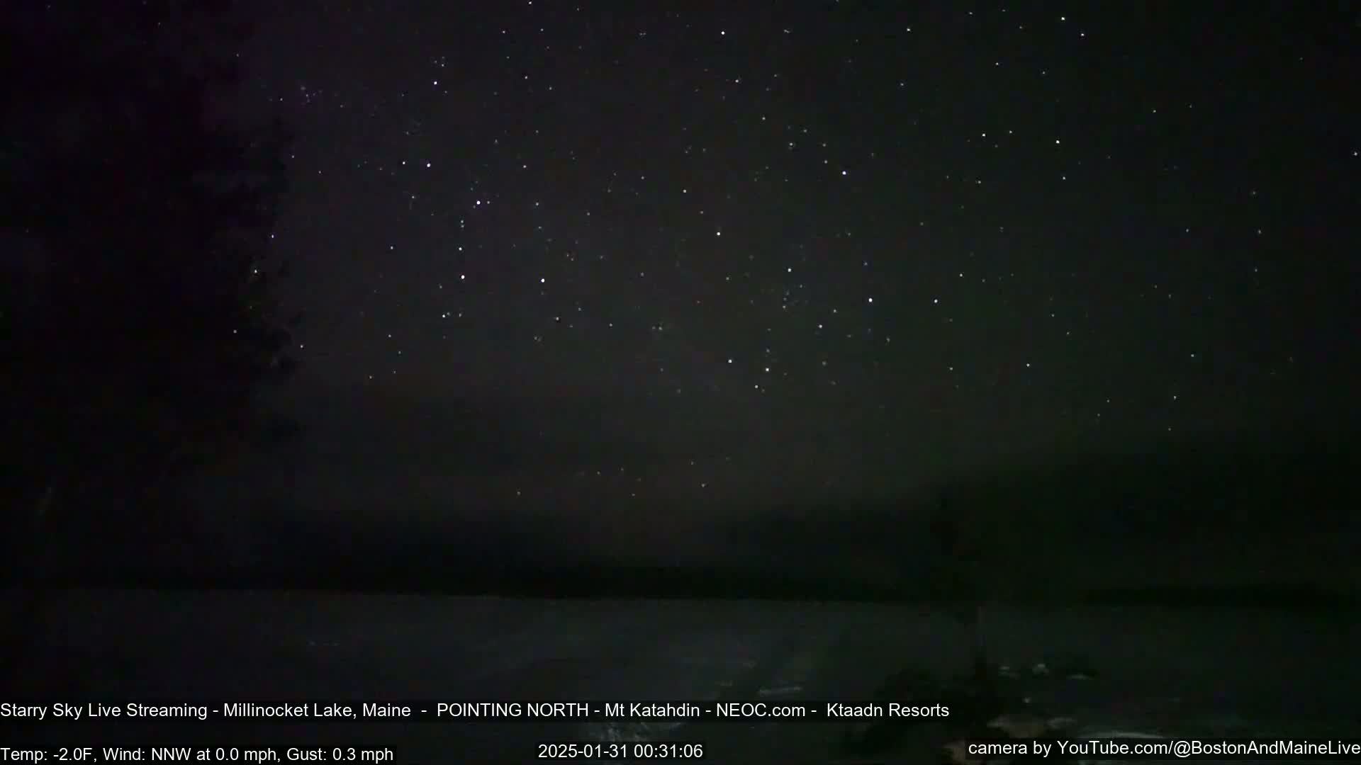 A nighttime view of a calm body of water under a clear, star-filled sky with a calm wind.