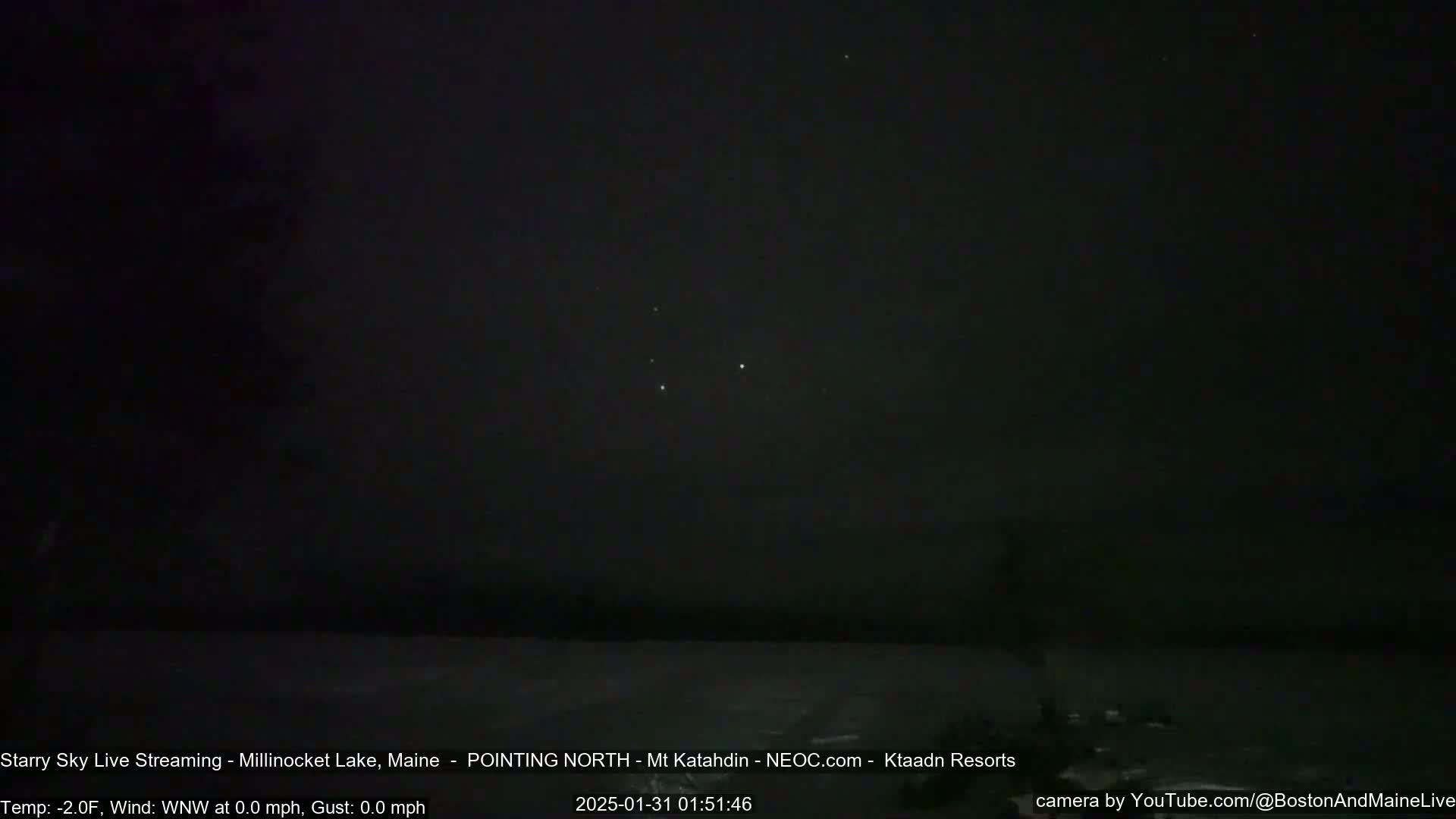 A dark, starry night sky over a calm body of water at -2°F with a calm wind.