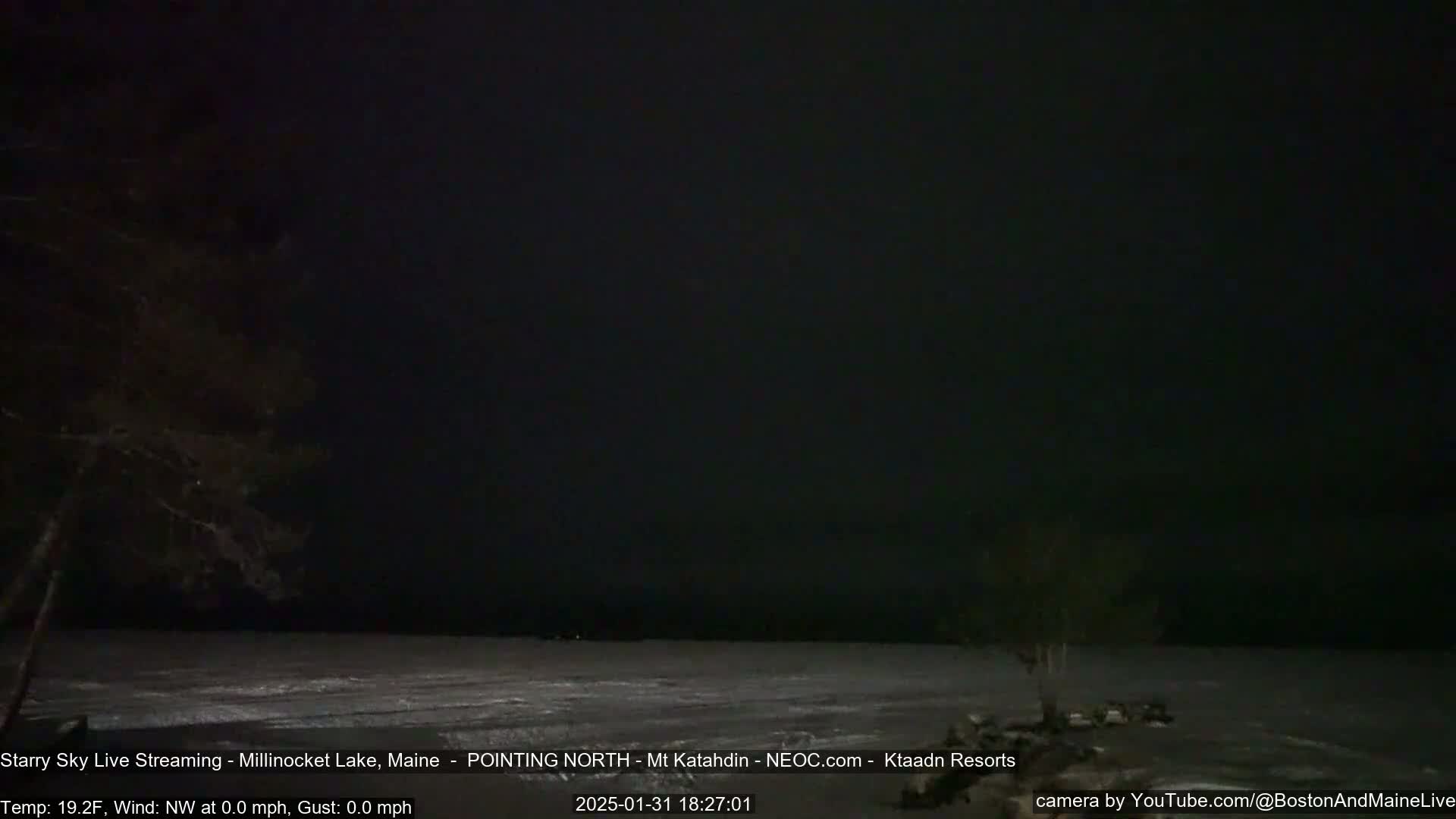 A dark, starry night scene shows a mostly frozen lake under a clear, black sky.