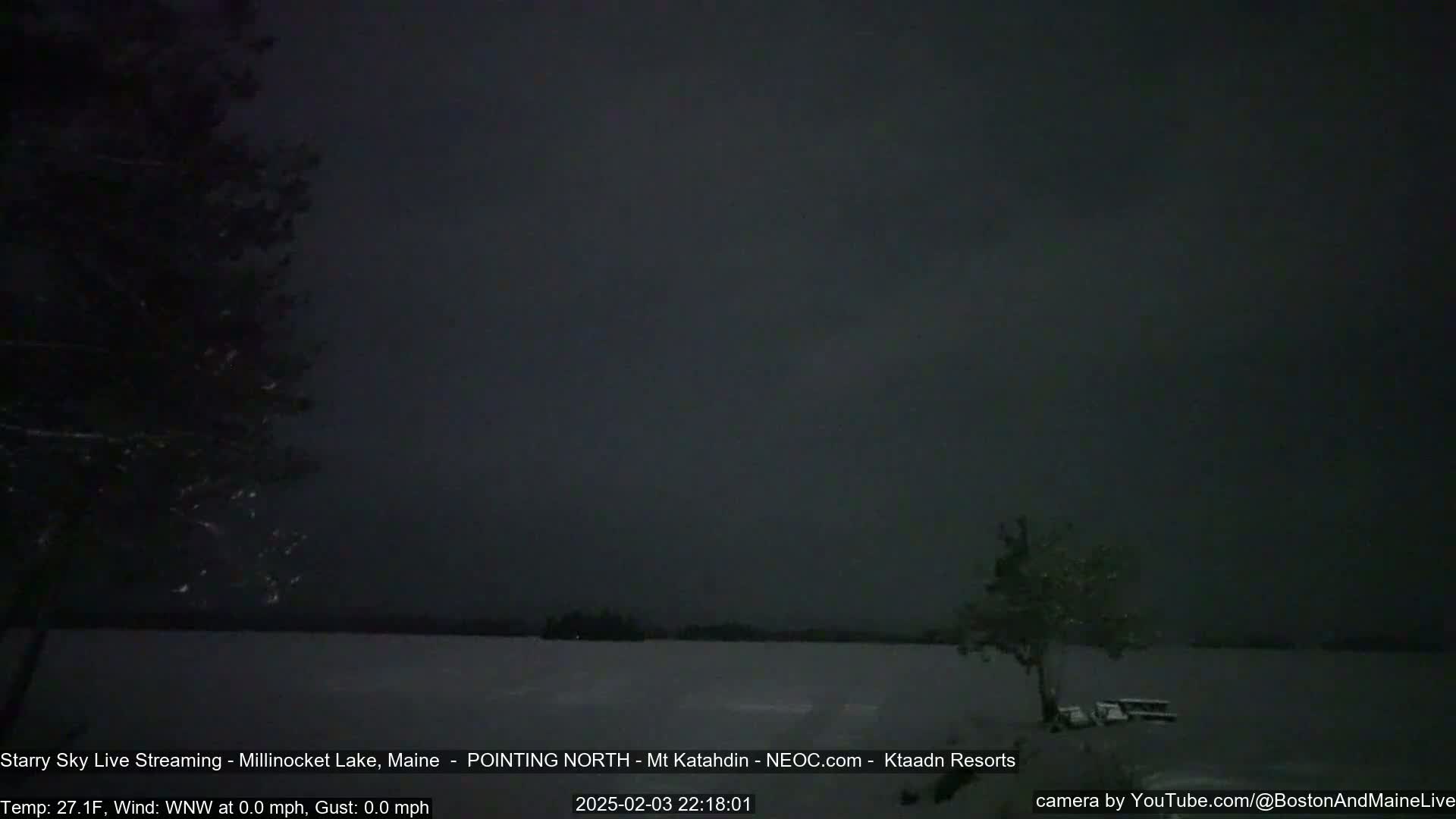 A snow-covered lake is visible under a dark, starry sky.