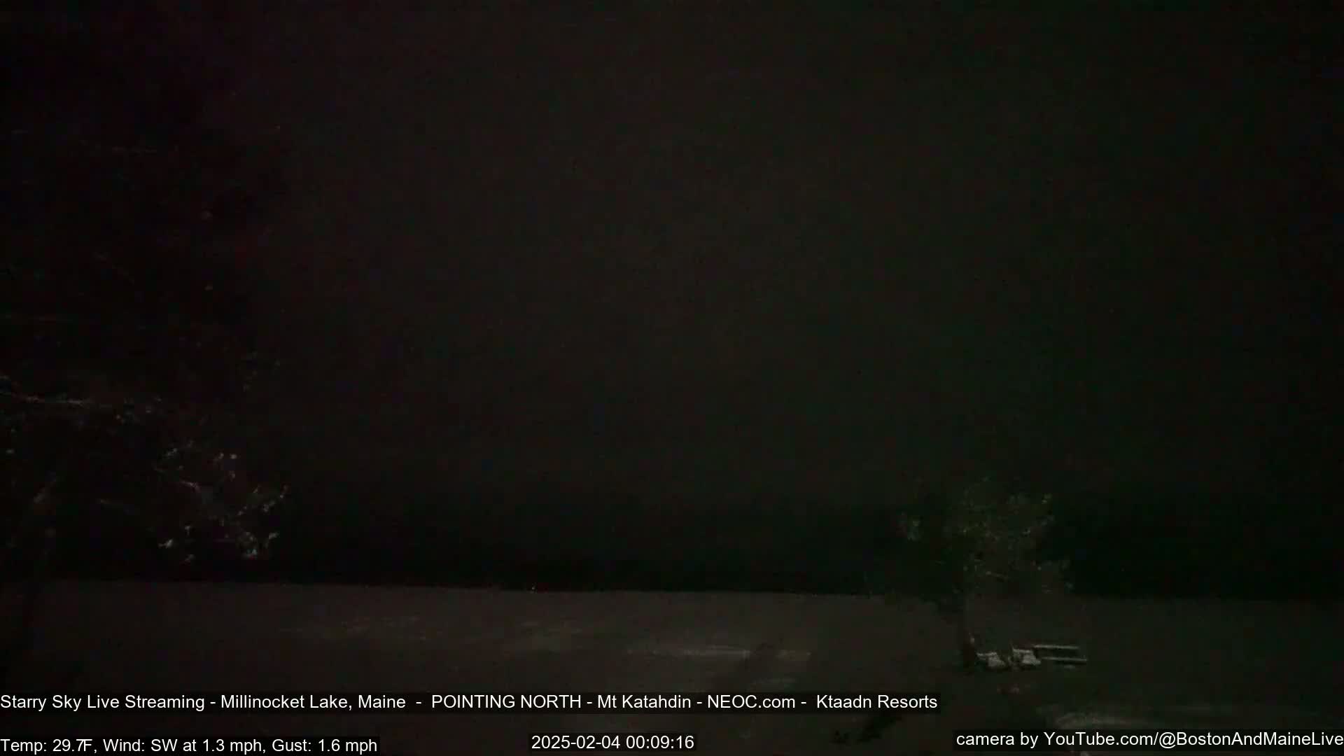 A dark, nighttime view of a snow-covered landscape, with a mostly clear sky and light southwest wind.