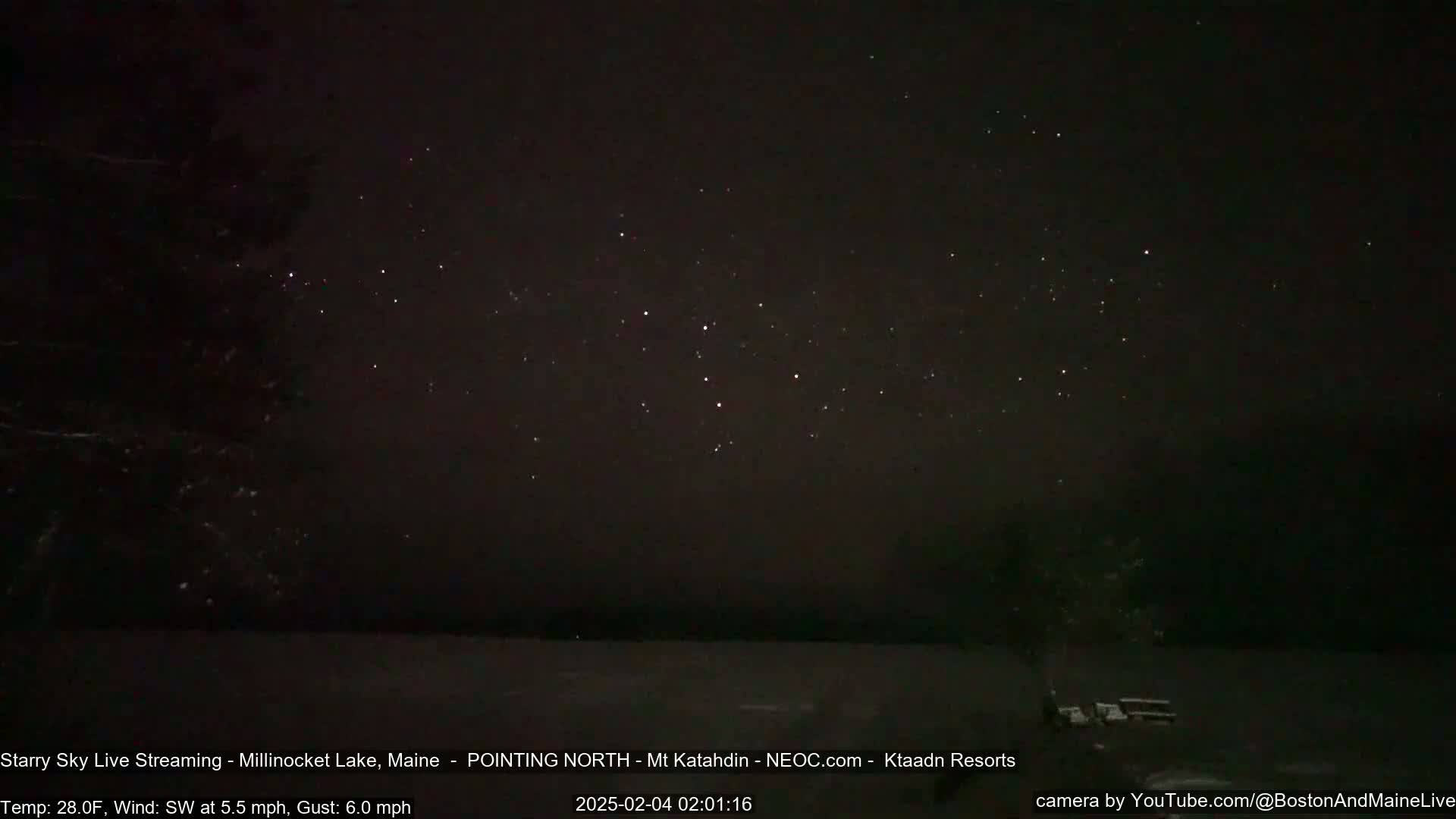A dark, starry night sky over a snow-covered lake, with a light southwest wind.