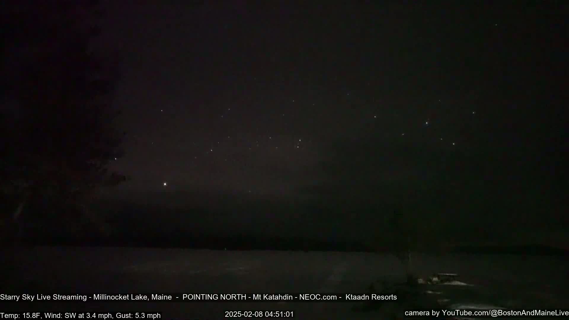 A nighttime long shot of a dark, clear sky filled with stars over a snow-covered landscape under a southwest wind of 3.4 mph with gusts up to 5.3 mph and a temperature of 15.8°F.