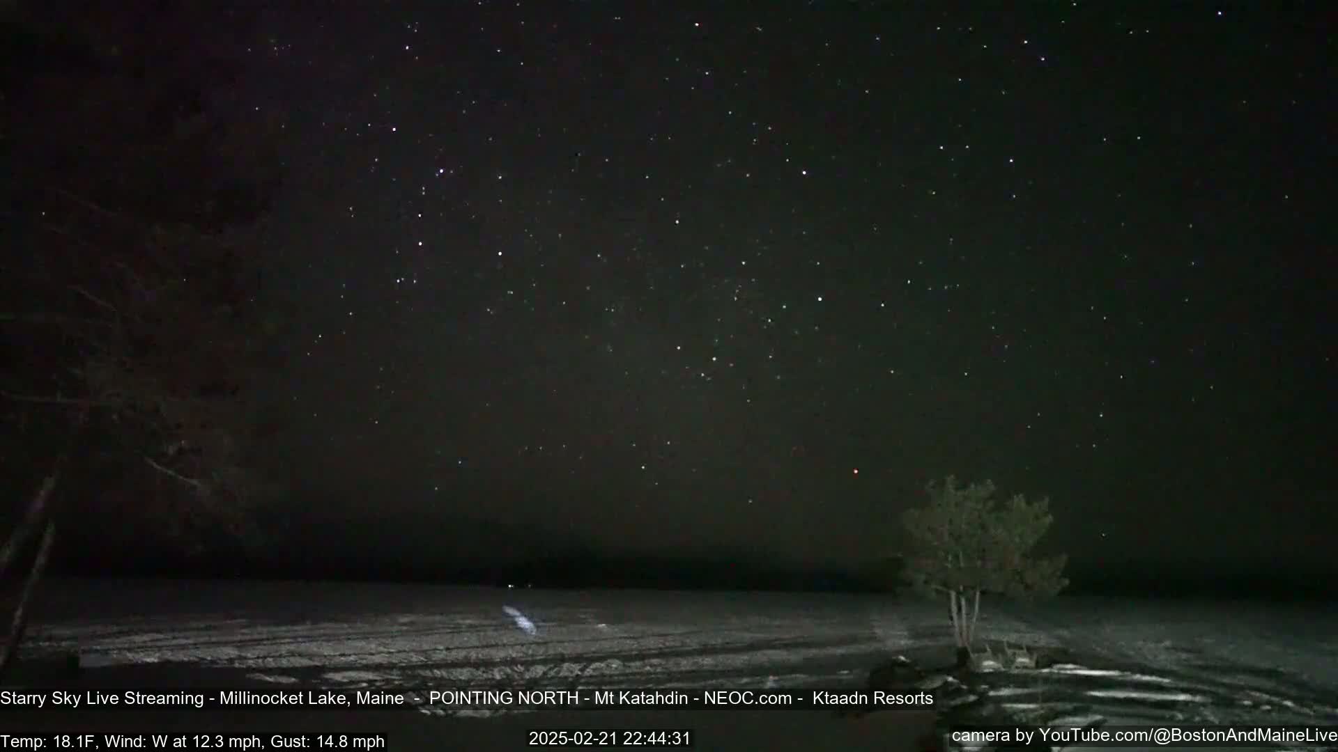 A snow-covered shoreline is visible under a clear, starlit night sky with a 18.1°F temperature and a 12.3 mph wind.