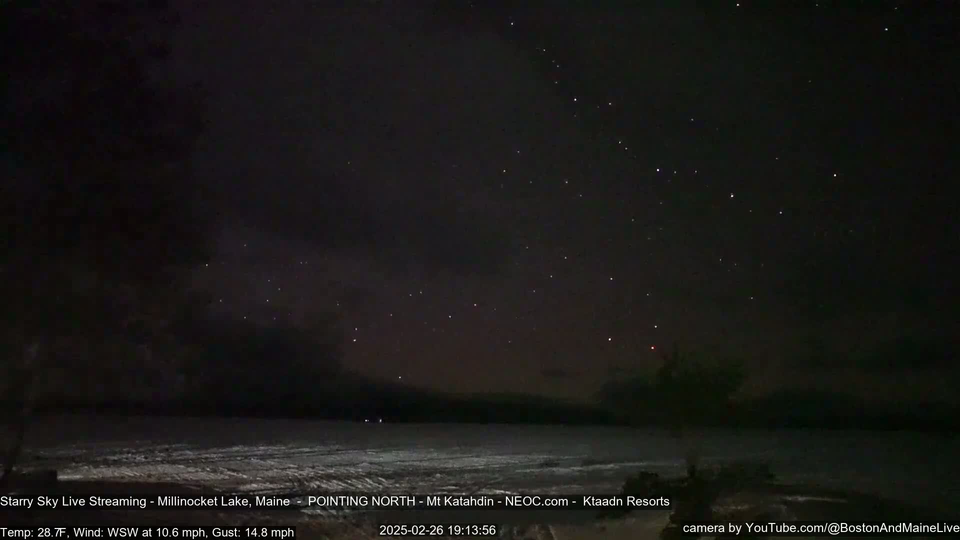 A dark, starry night sky over a calm body of water, with a light wind blowing.