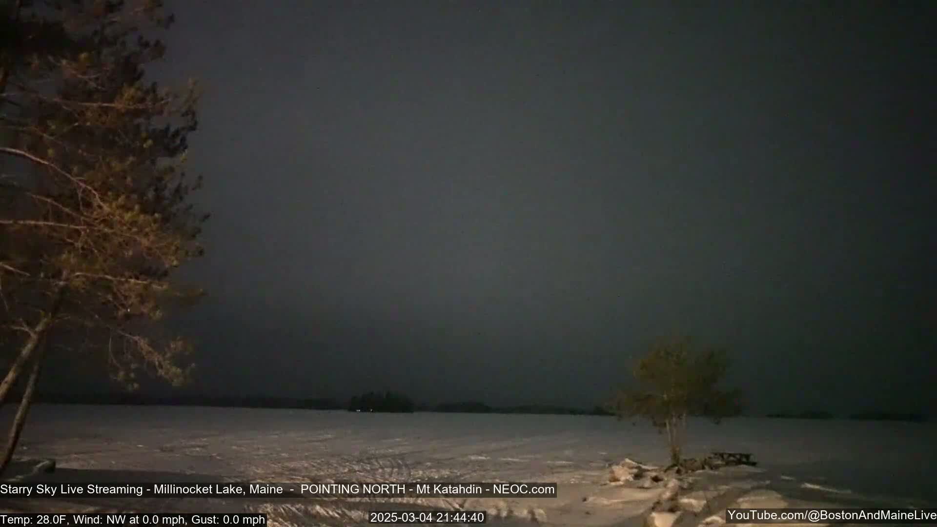 A snow-covered landscape at night under a dark, mostly clear sky is illuminated by sparse stars.
