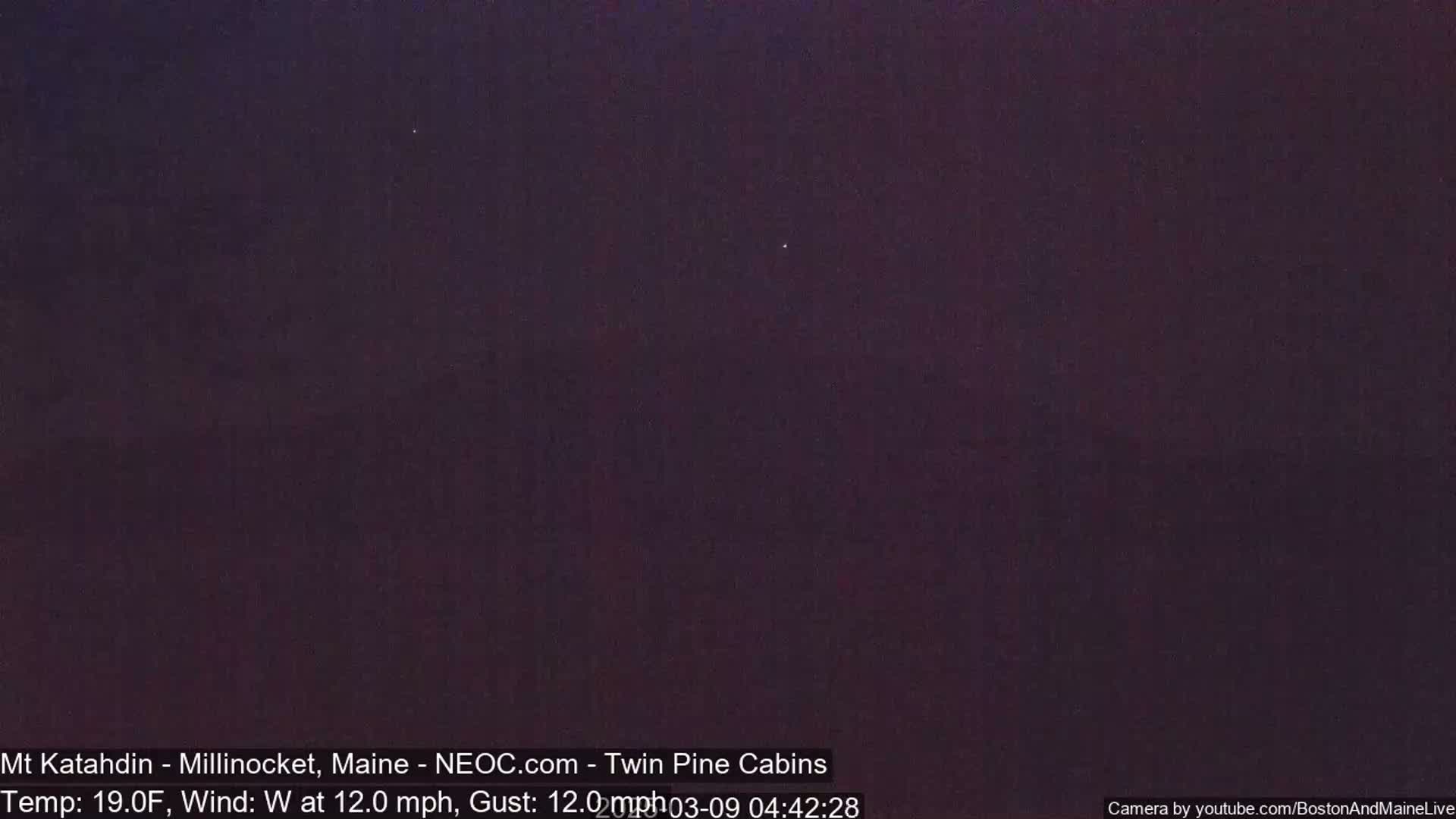 A dark, nighttime outdoor scene with a few visible stars under a clear sky, showing a west wind at 12 mph with gusts of 12 mph and a temperature of 19 degrees Fahrenheit.