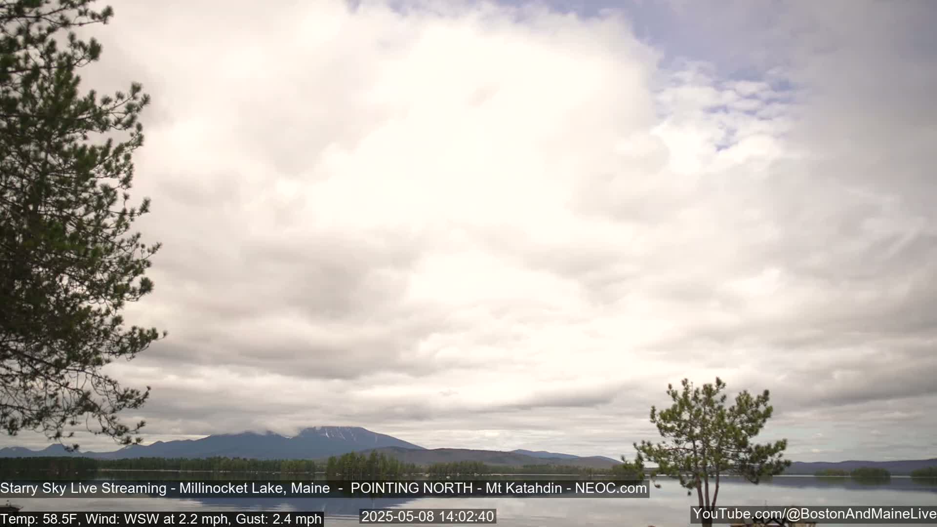 A partly cloudy sky over a lake with mountains in the distance, under a light wind.