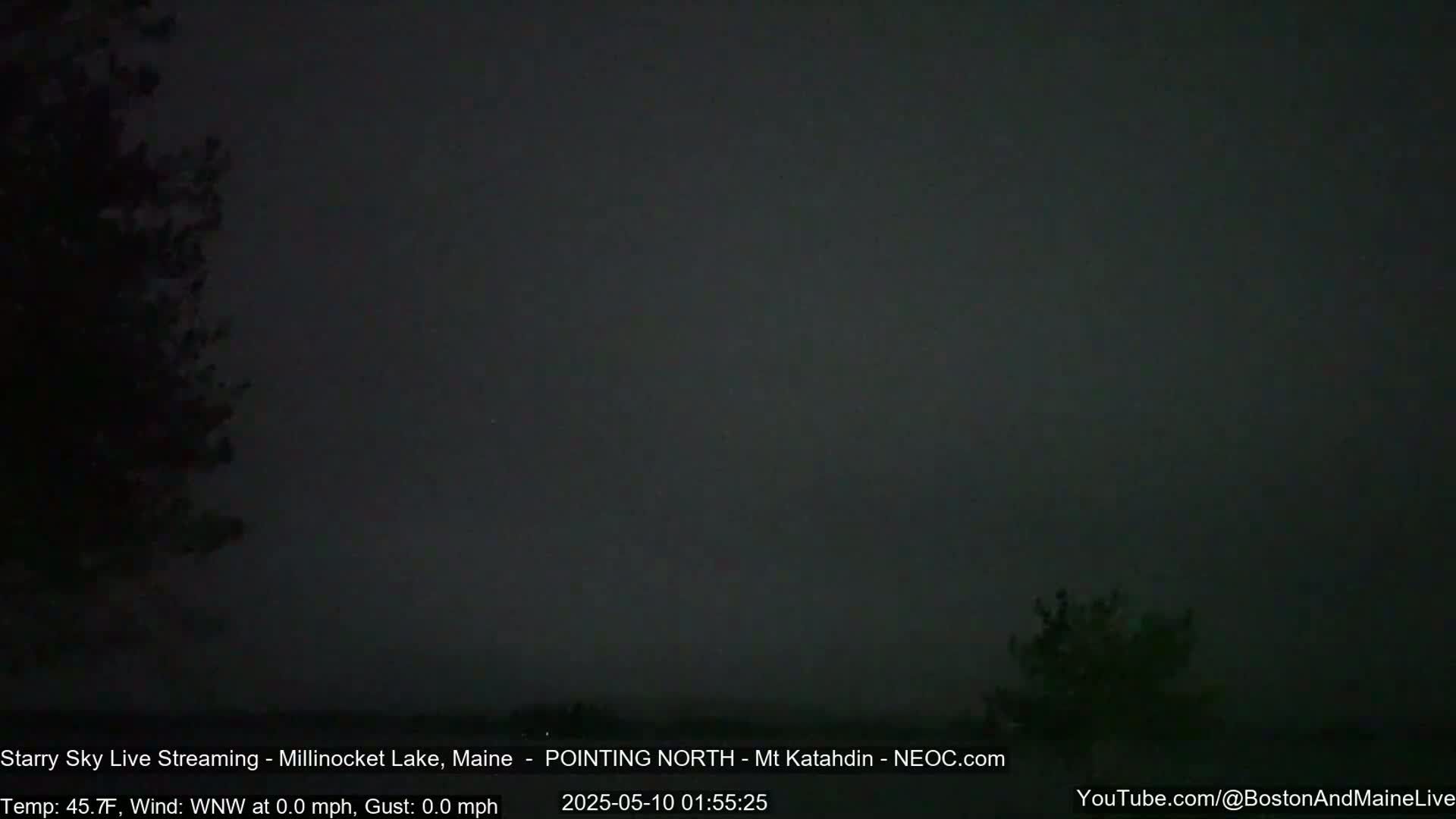 A dark, nighttime scene shows a mostly overcast sky with some silhouetted trees at the edges.