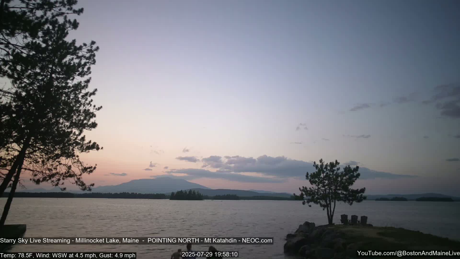 A nighttime view of a calm lake under a starry sky, with a slight wind blowing from the west-northwest.