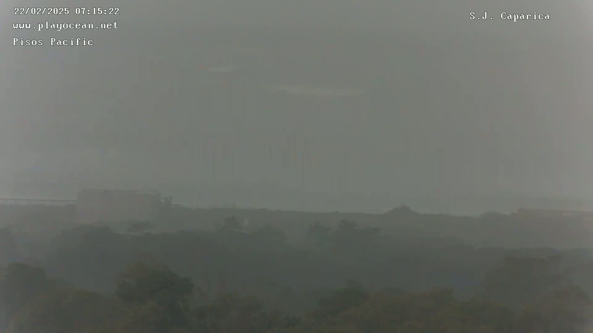 A hazy, overcast sky obscures a distant view of a low-lying landscape with dark green vegetation.