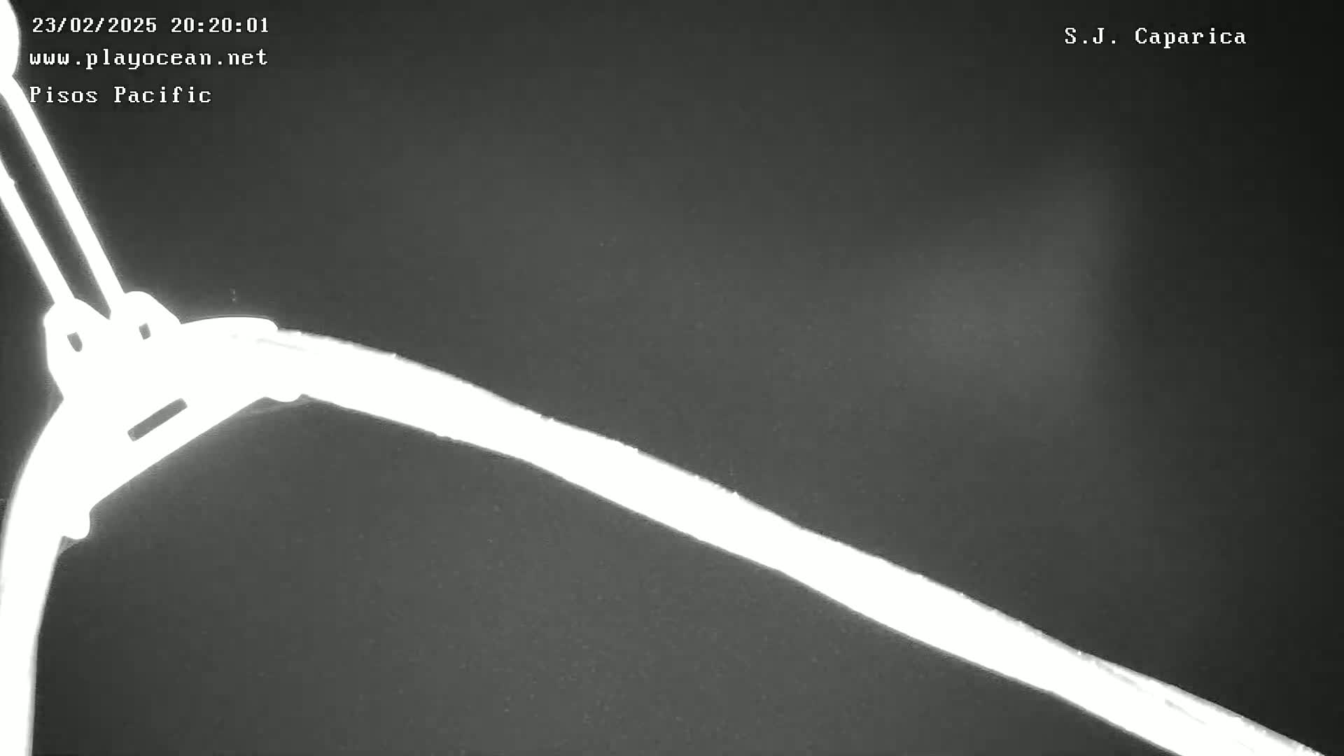 A low-light, nighttime image shows a bright white line diagonally across a dark gray surface, possibly a road or walkway.
